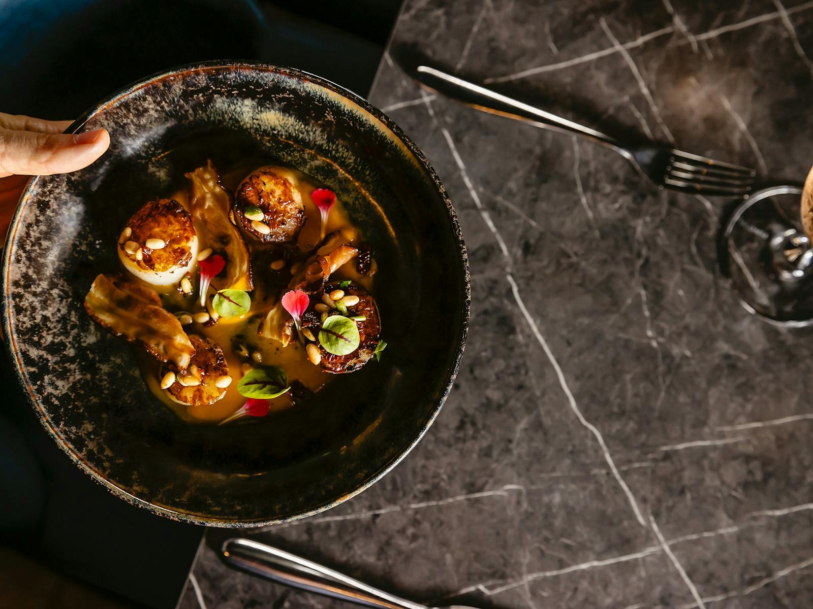 Top view from a dark plate with pan seared scallops being served on a table Top view from a dark plate with pan seared scallops being served on a table