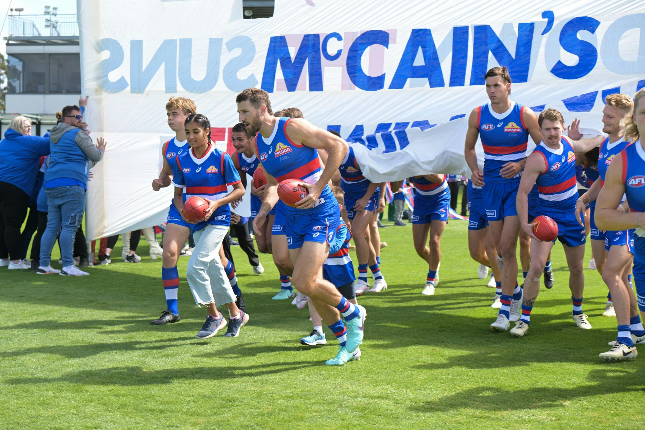 Football players running through the banner
