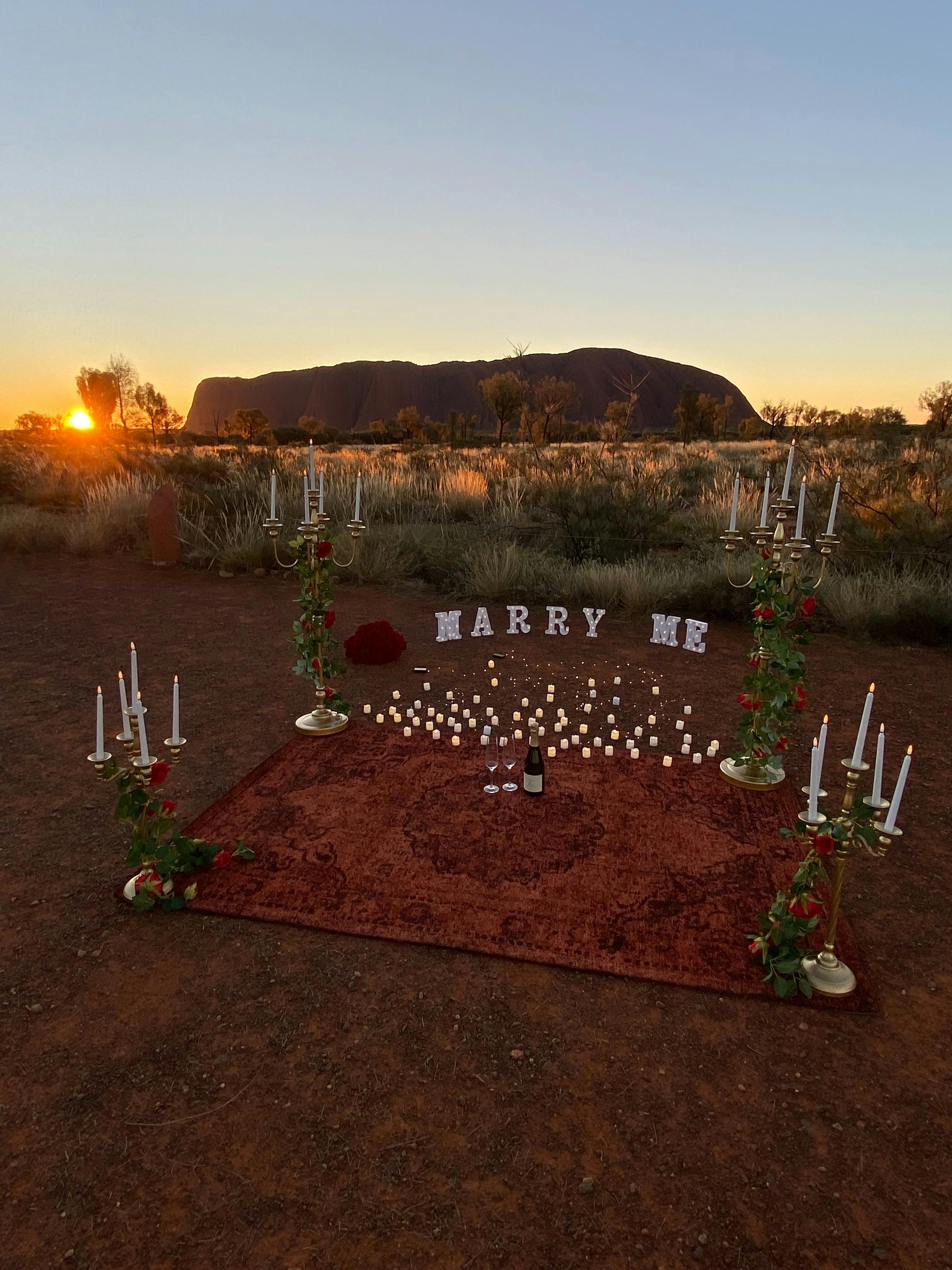 Blue, purple and yellow sunset over Uluru. Candles, and Marry me sign.