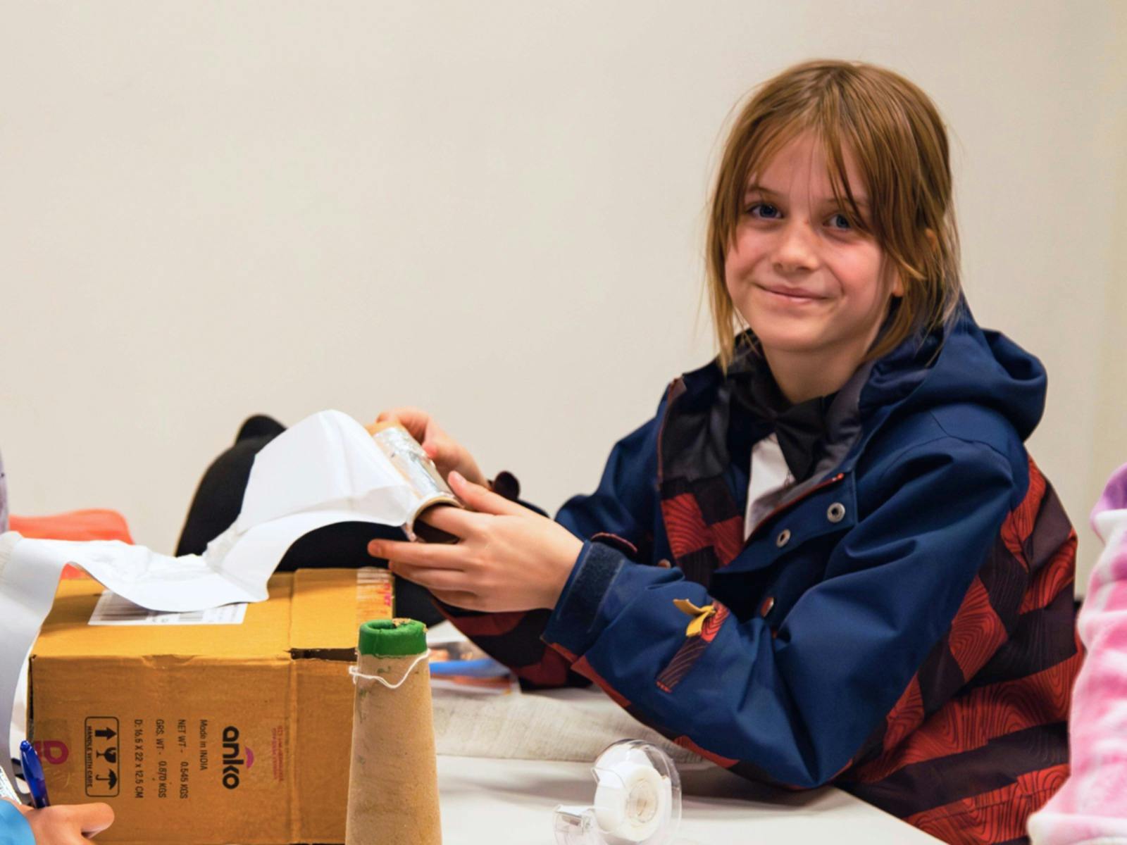 A girl holds up her work during a Science Workshop.