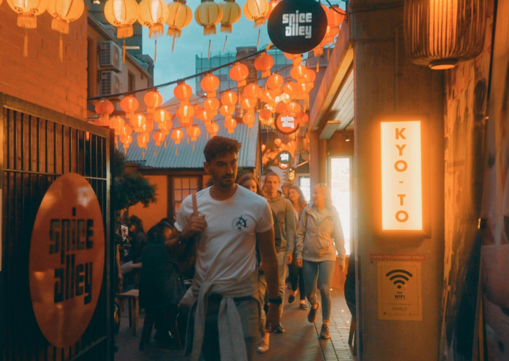 A man leading a group walking through Spice Alley in Sydney