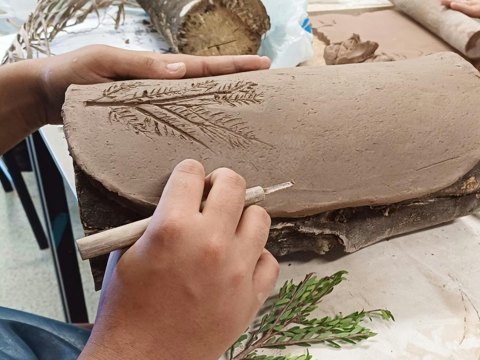 Hands working on shaping a traditional coolamon vessel