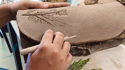 Hands working on shaping a traditional coolamon vessel
