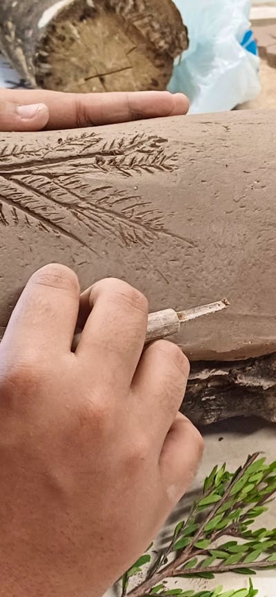 Hands working on shaping a traditional coolamon vessel