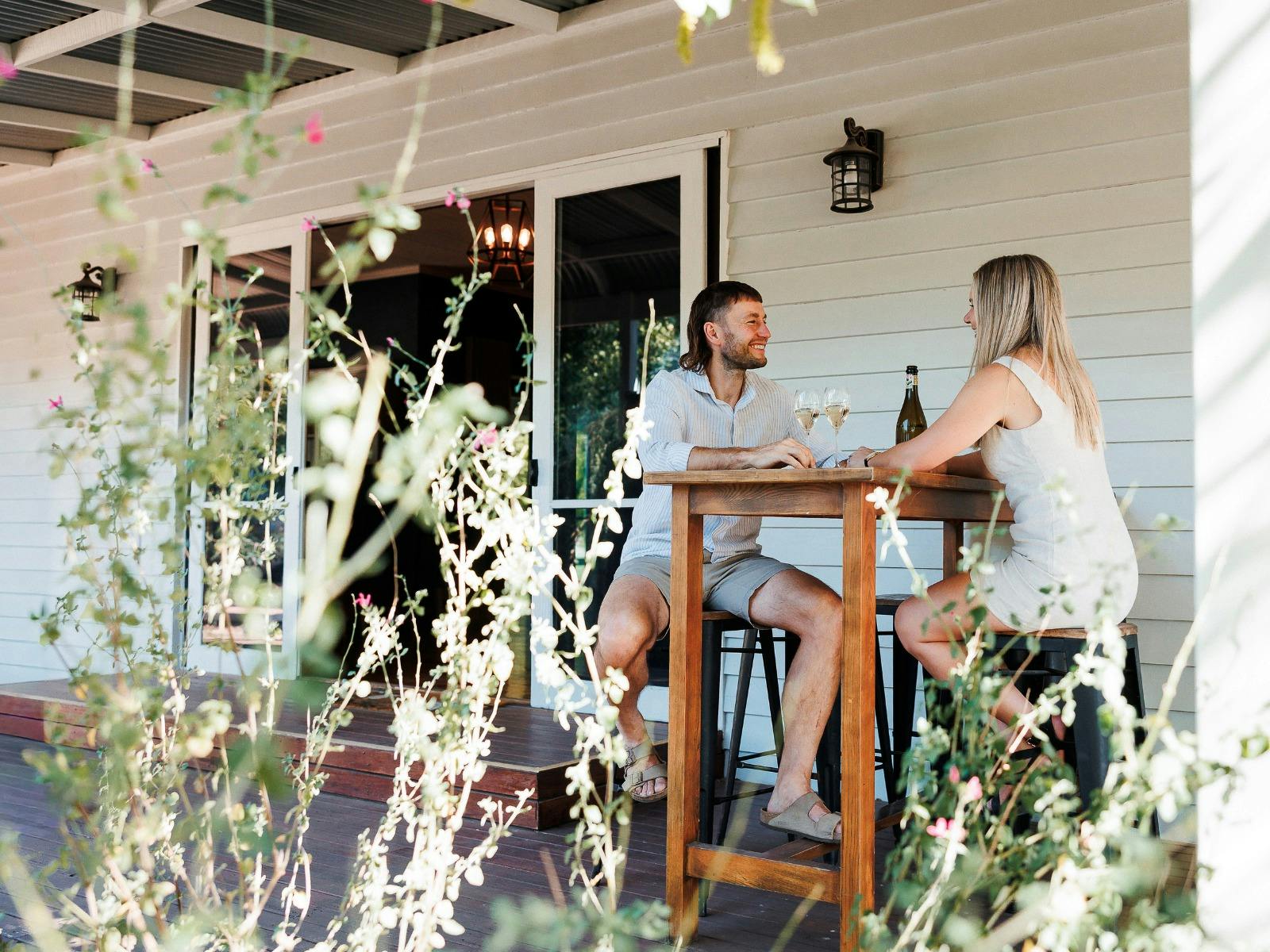 Guests sitting on deck of Dal Zotto Homestead accommodation surrounded be flowers