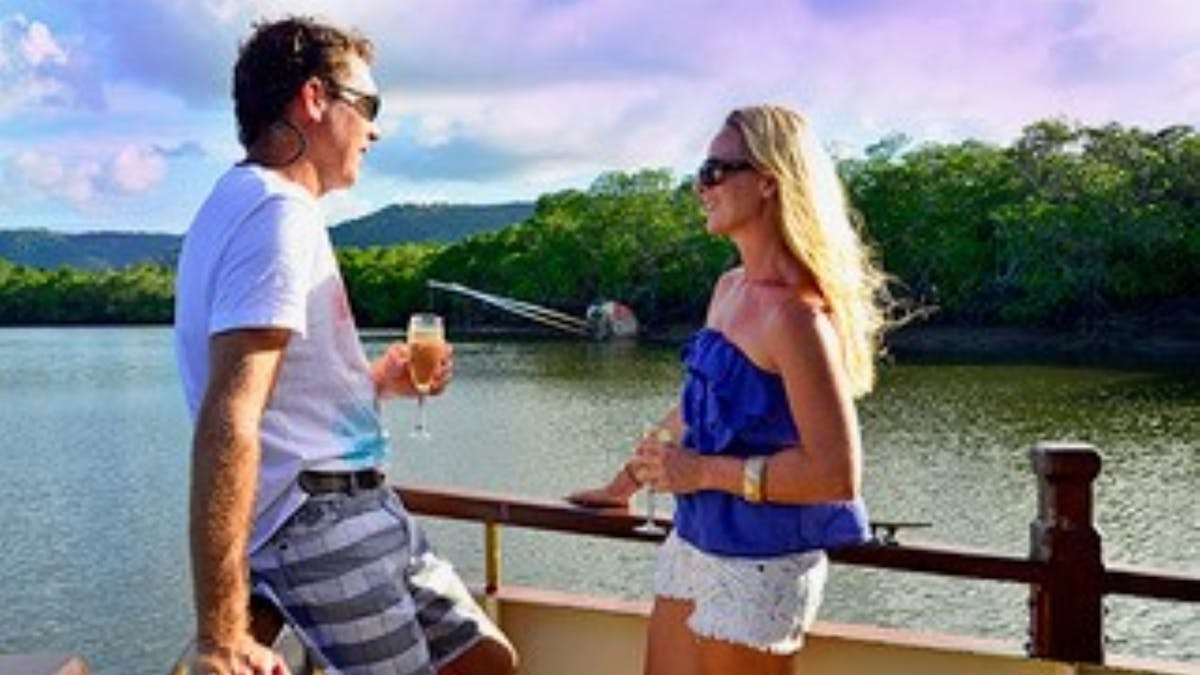 Couple enjoying a cold drink, cruising up the estuary on Lady Douglas in Port Douglas, Queensland