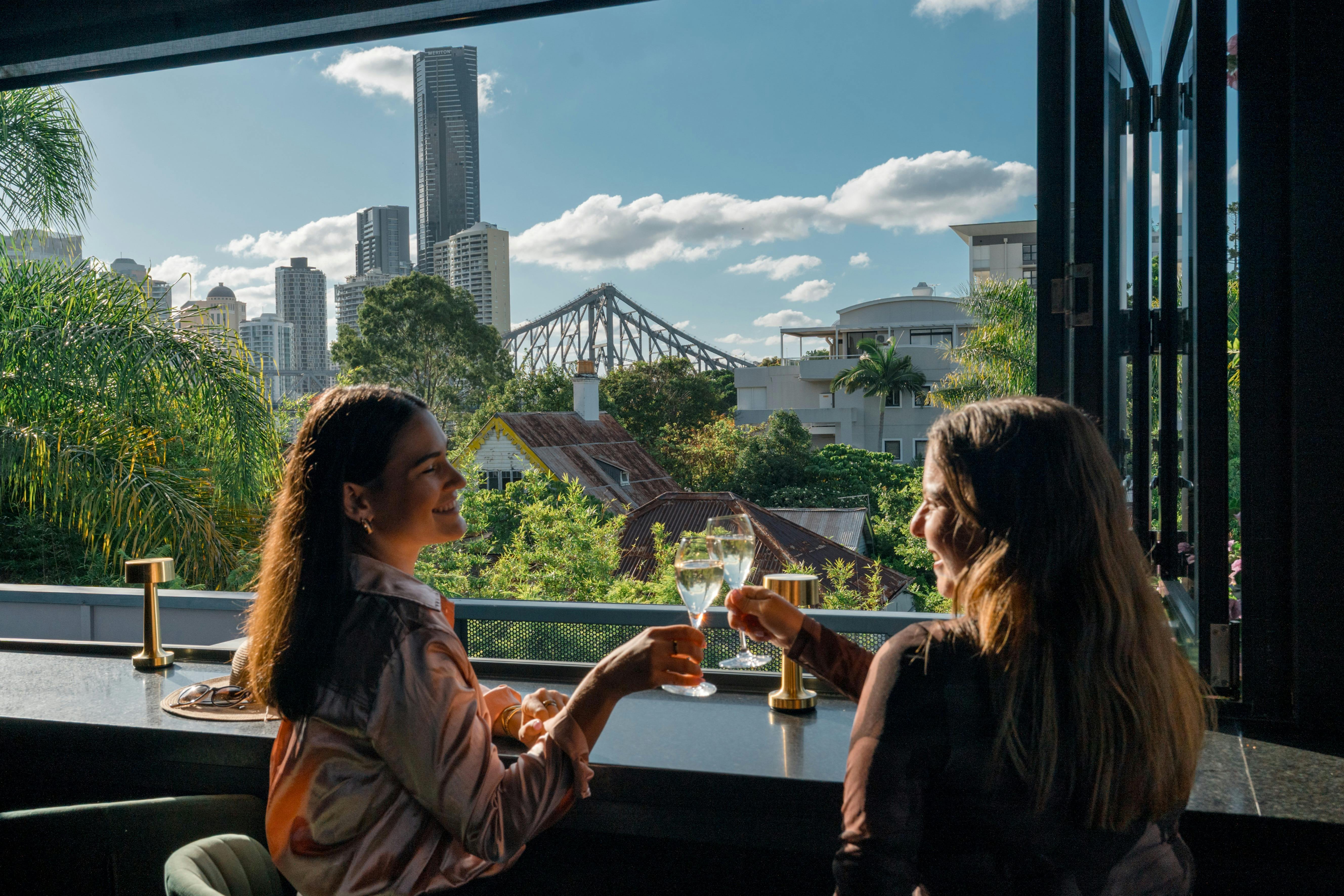 two women drinking wine at rooftop bar