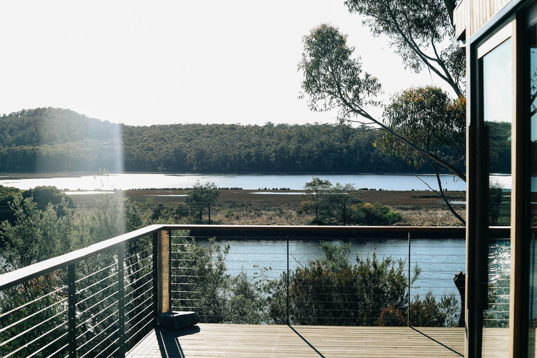 A timber deck with timber railing looks out across river and native vegetation.