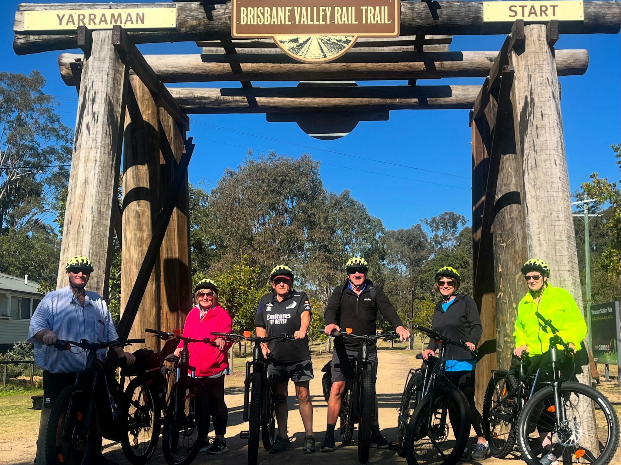 A group of 6 riders stand in front of a wooden structure, they are holding bikes and wearing helmets A group of 6 riders stand in front of a wooden structure, they are holding bikes and wearing helmets