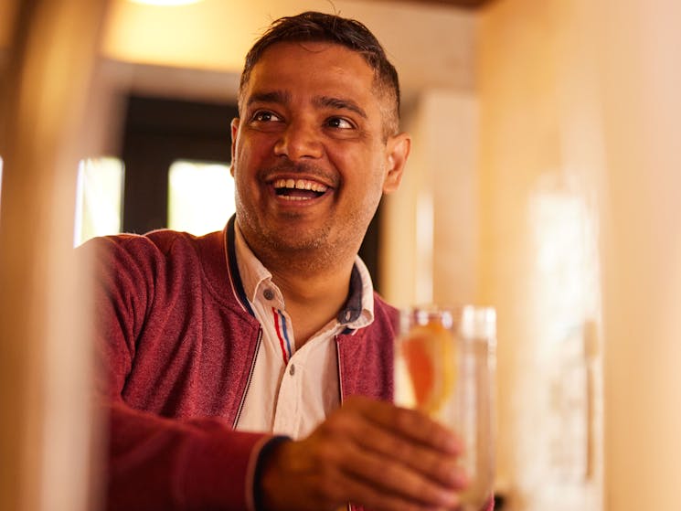Guest laughs, holding cocktail glass