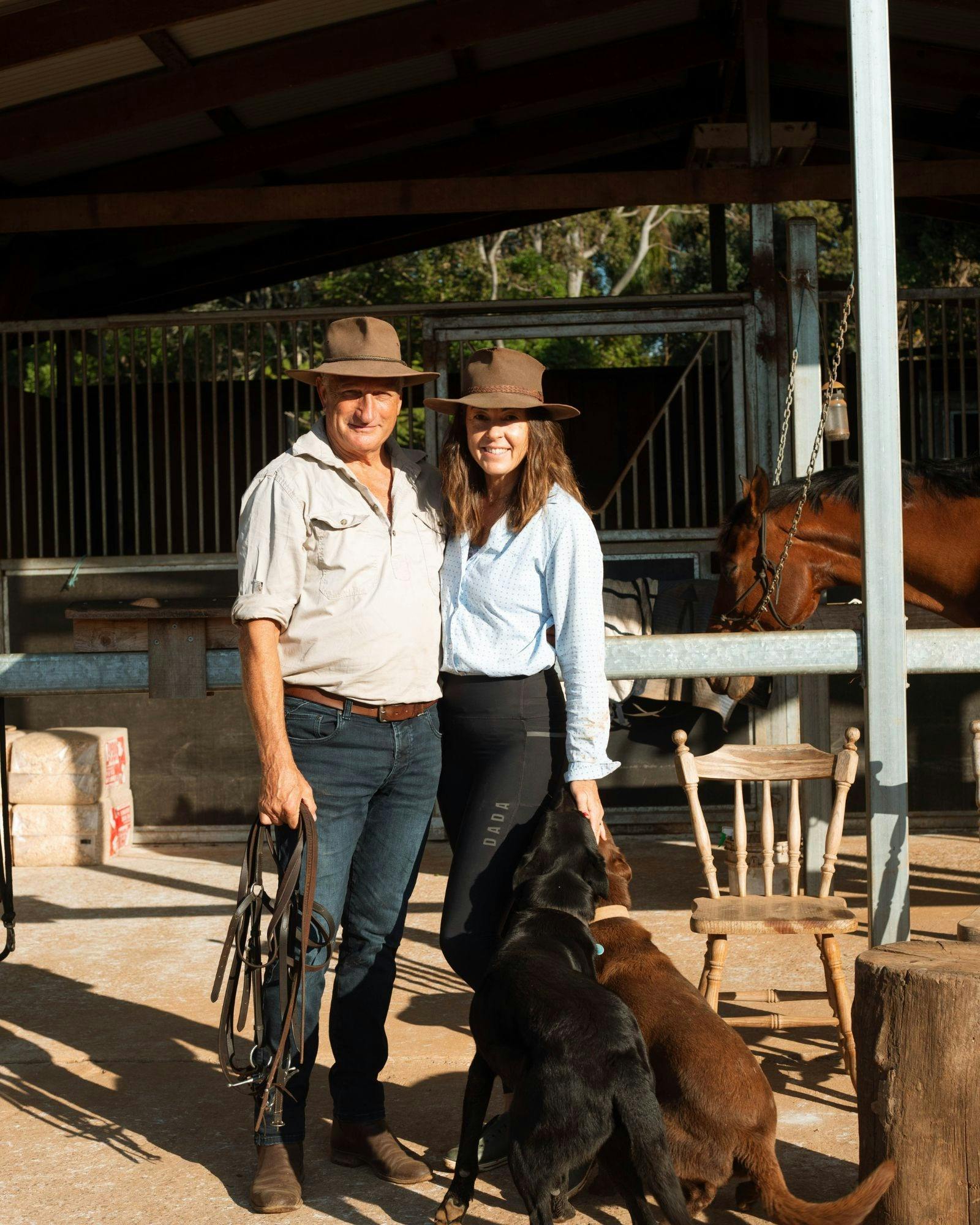 ヒディとマックがヒディ＆カンパニーの納屋のそばに犬と一緒に立っています。