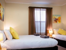 Second bedroom with queen and single beds, under stairs walk in robe.