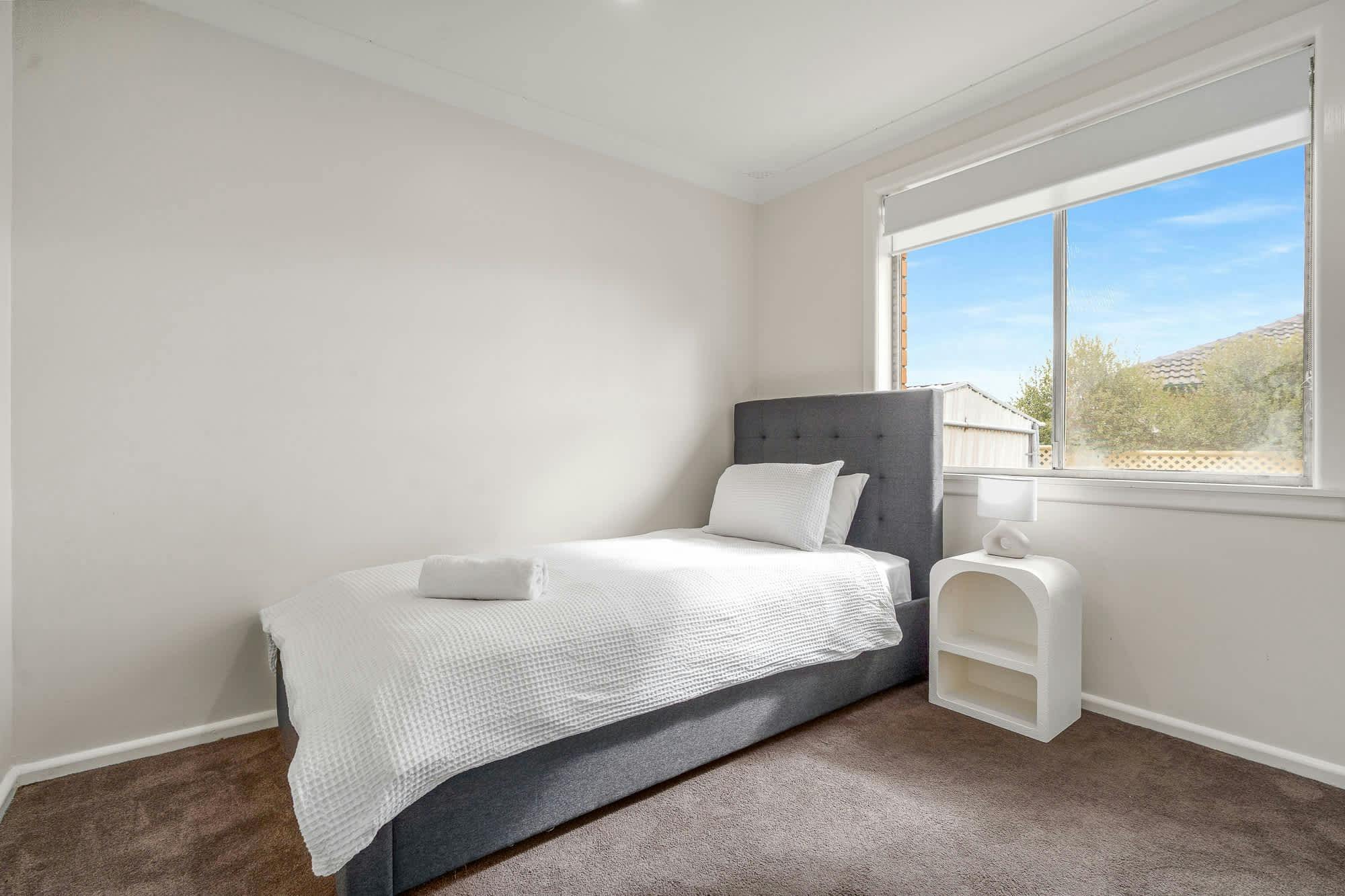 Single bed with side table and wardrobe, lots of natural light