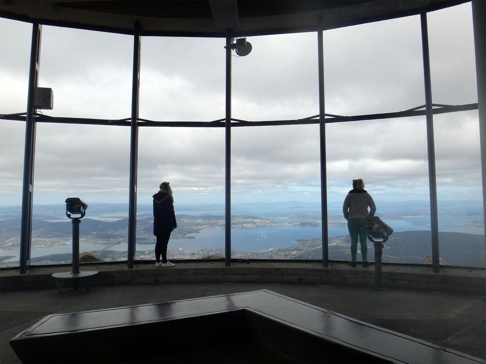 Passengers standing inside the Observation Shelter and looking out at the views over Hobart.