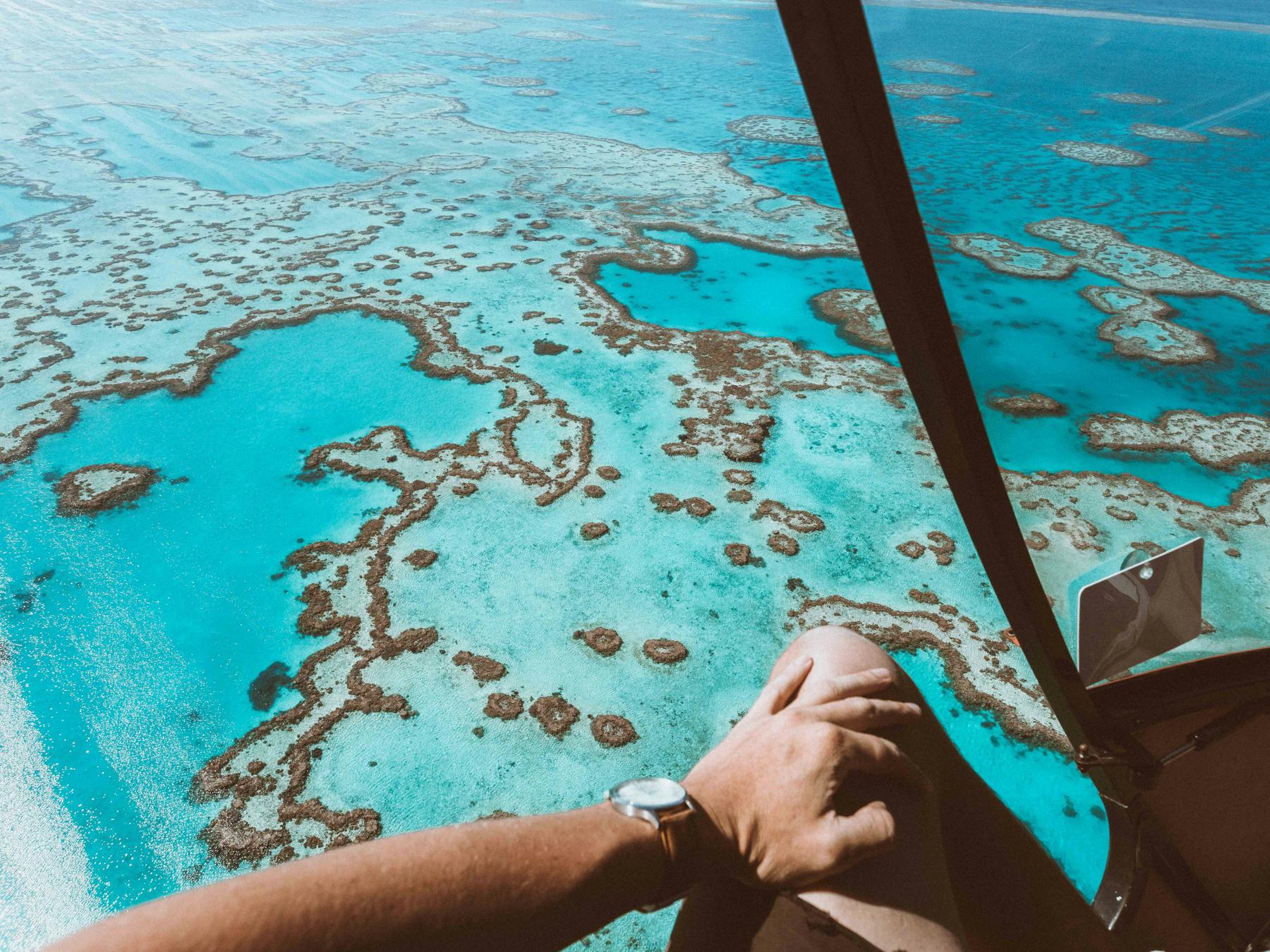 Aerial view of the calm turquoise water surrounded by coral reefs including heart shaped reef