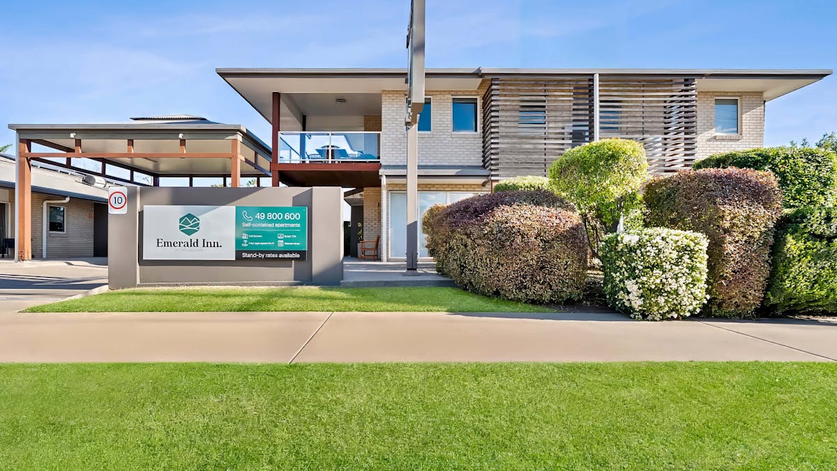 The modern exterior of the Emerald Inn motel with well maintained gardens & grounds.
