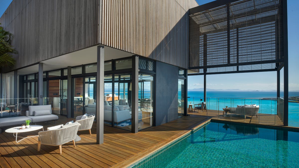 Contemporary residence with a private pool, and ocean-view seating areas under a clear sky.