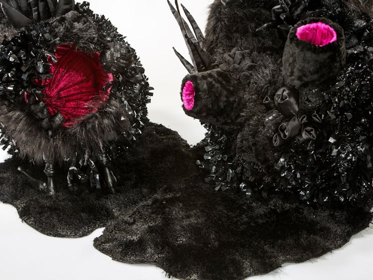 A pink and black large sculpture made of textiles and found furniture