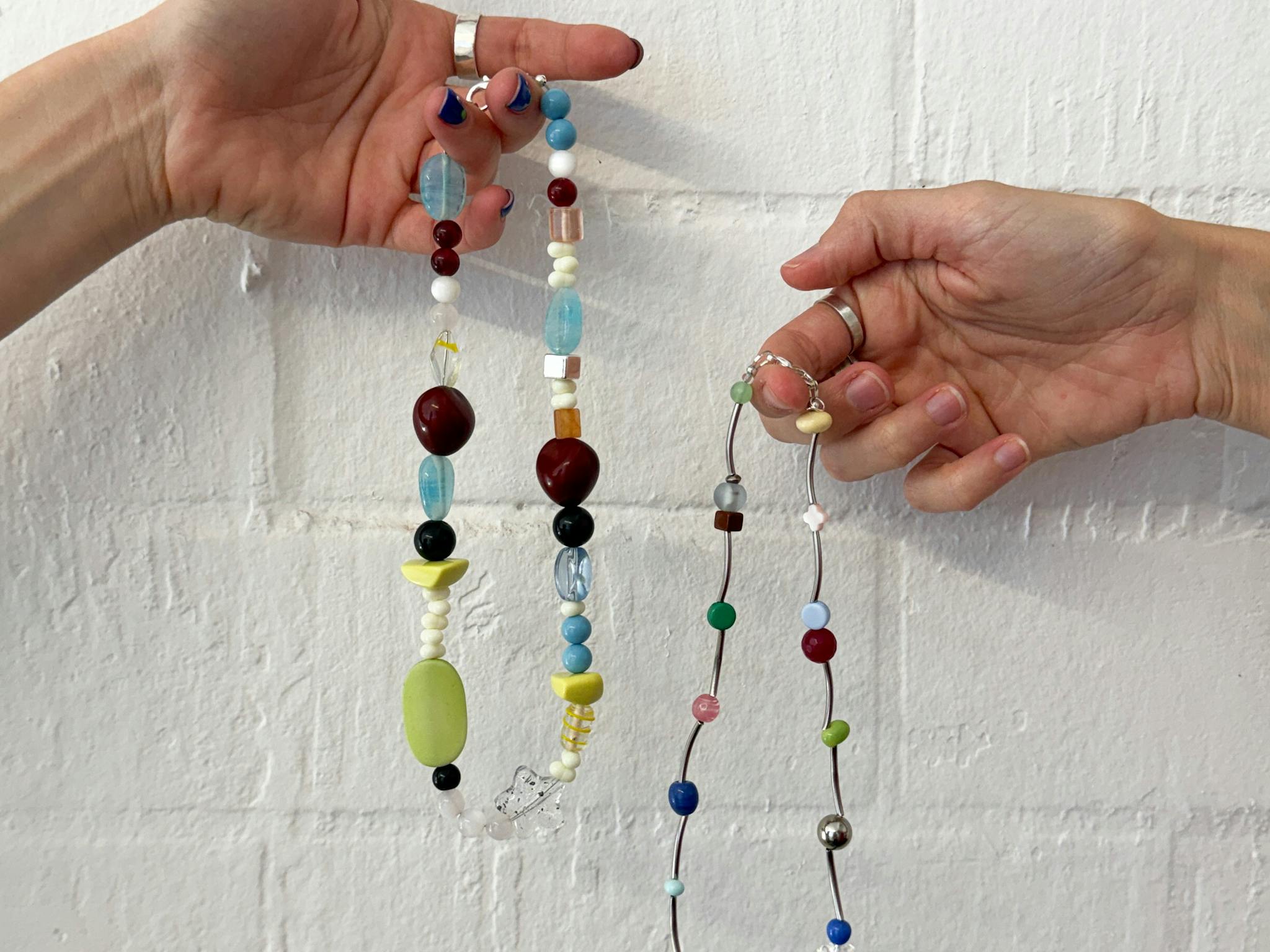 Two hands holding colourful beaded necklaces Two hands holding colourful beaded necklaces