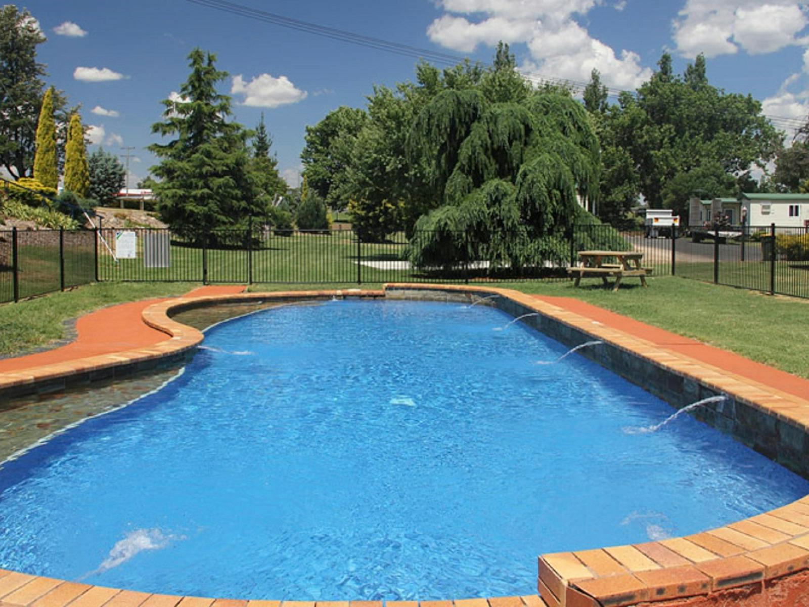 Swimming Pool in foregroung. Green lawn and trees in background.