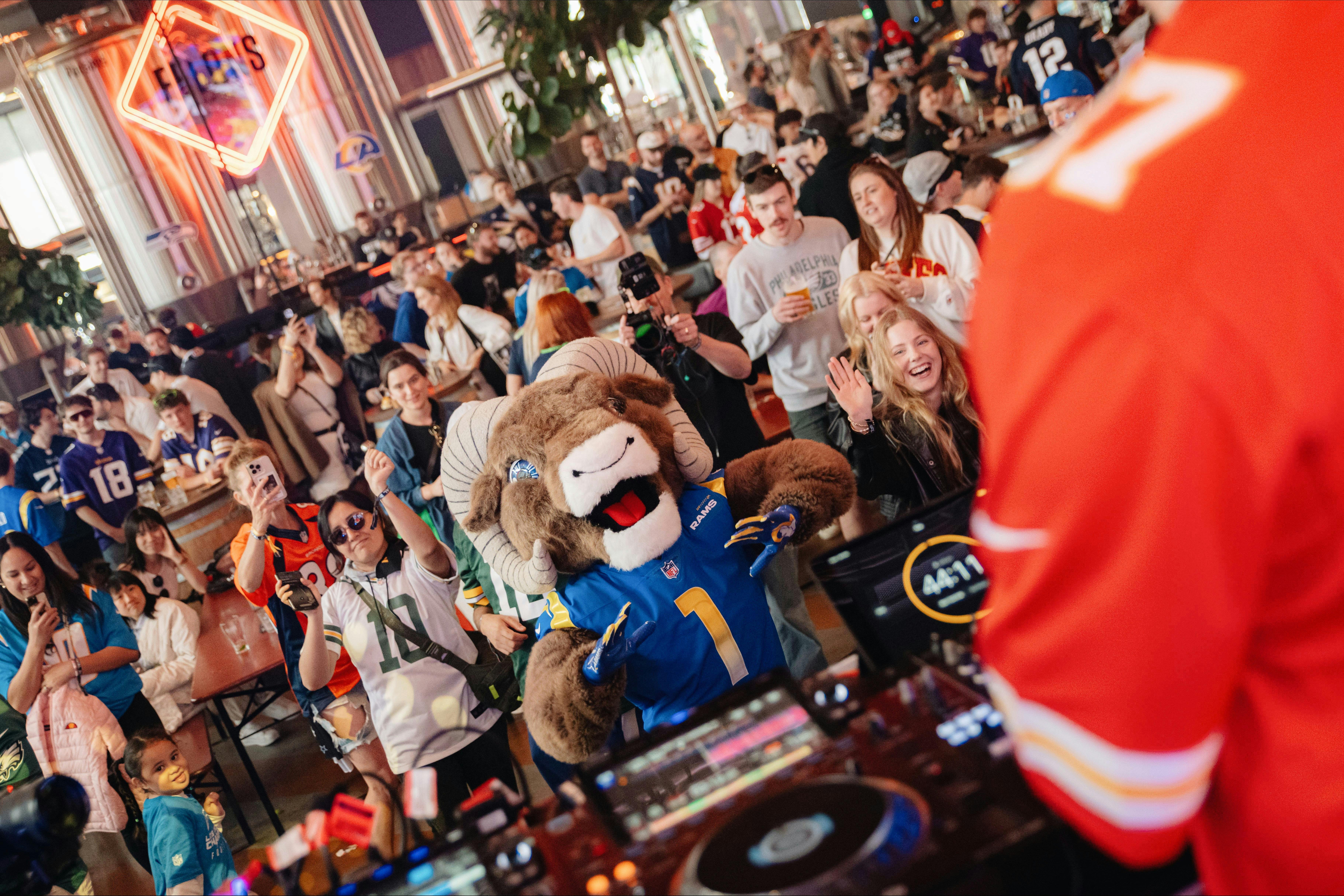 a large crowd of people dancing at an NFL Watch Party including the LA Rams Mascot