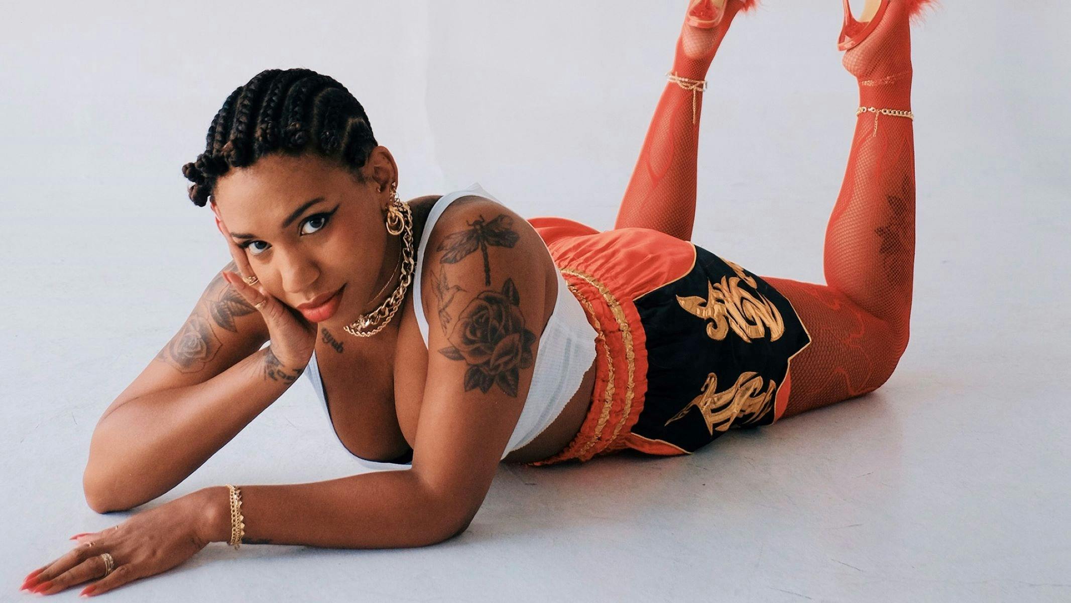 A tattooed person lies on the floor