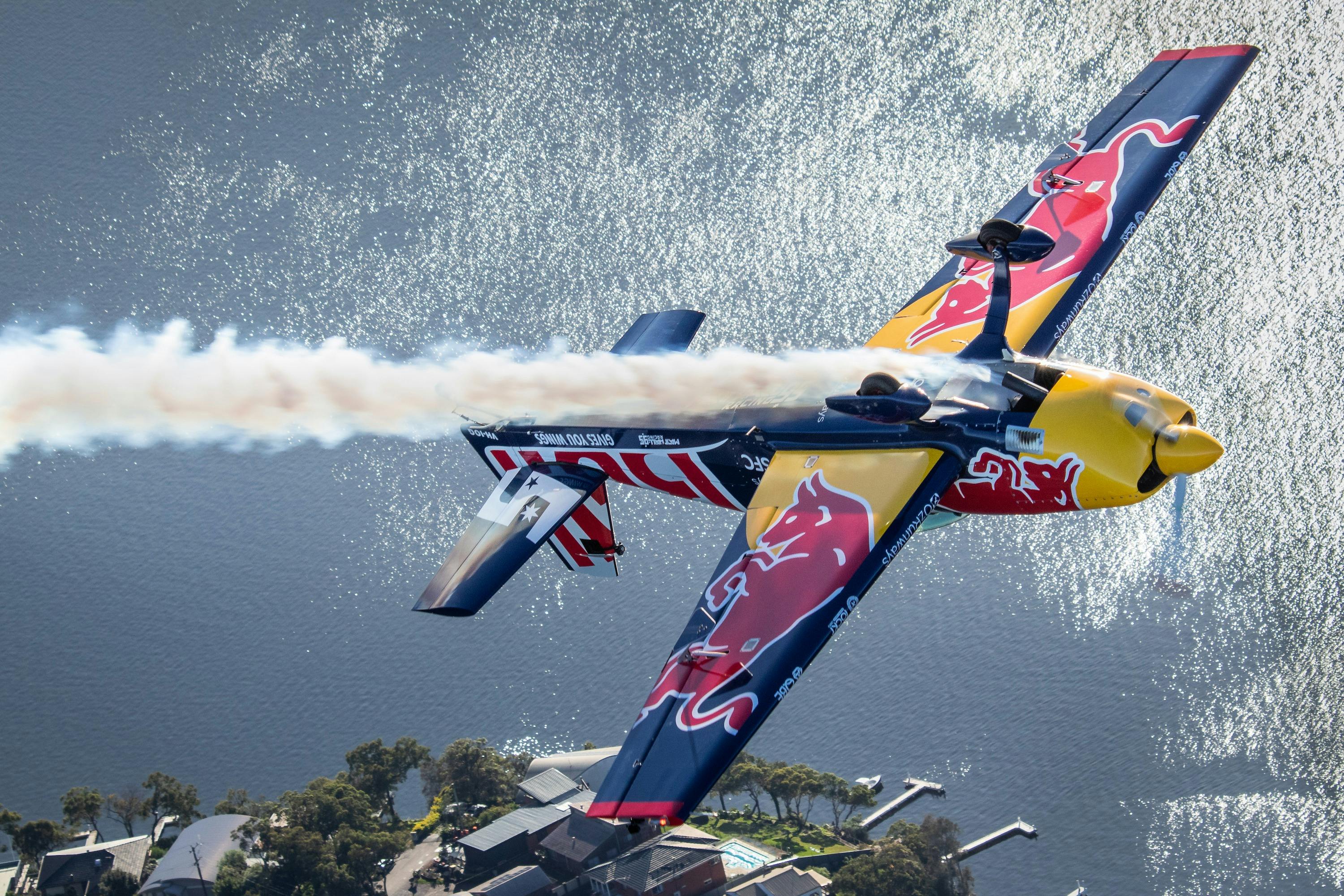 Matt Hall Racing Red Bull aerobatic aeroplane flying inverted with smoke on over Lake Macquarie, NSW