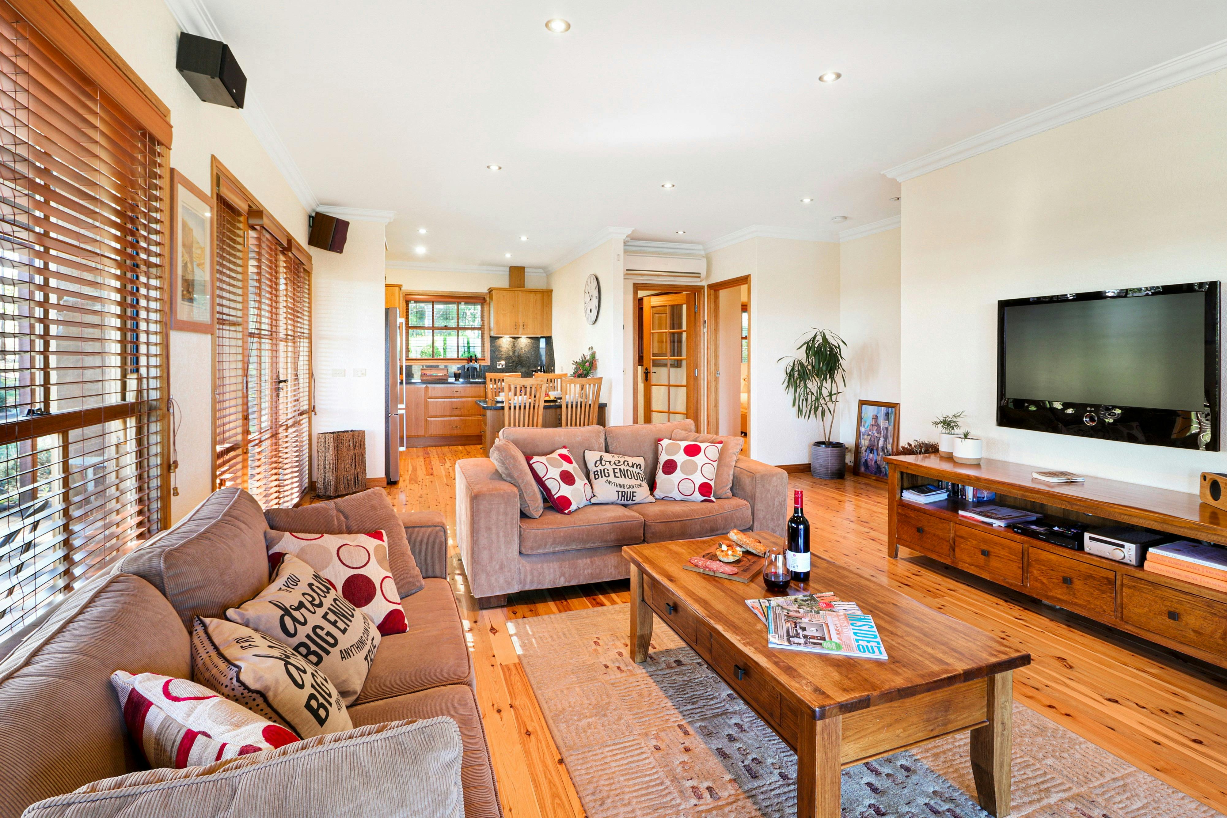 Stylish living lounge area with large TV, sound system and adjoining open plan kitchen
