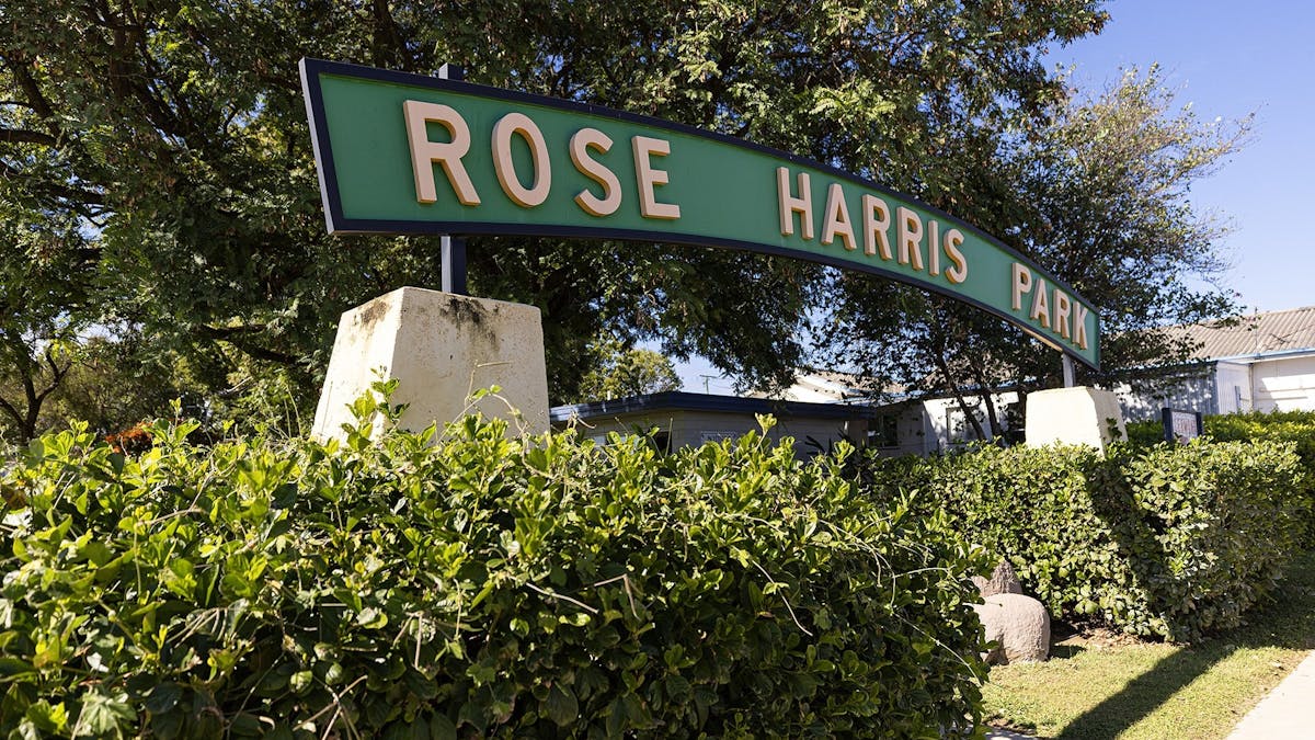 Green entrance sign to Rose Hill Park, with gardens around and footpaths.