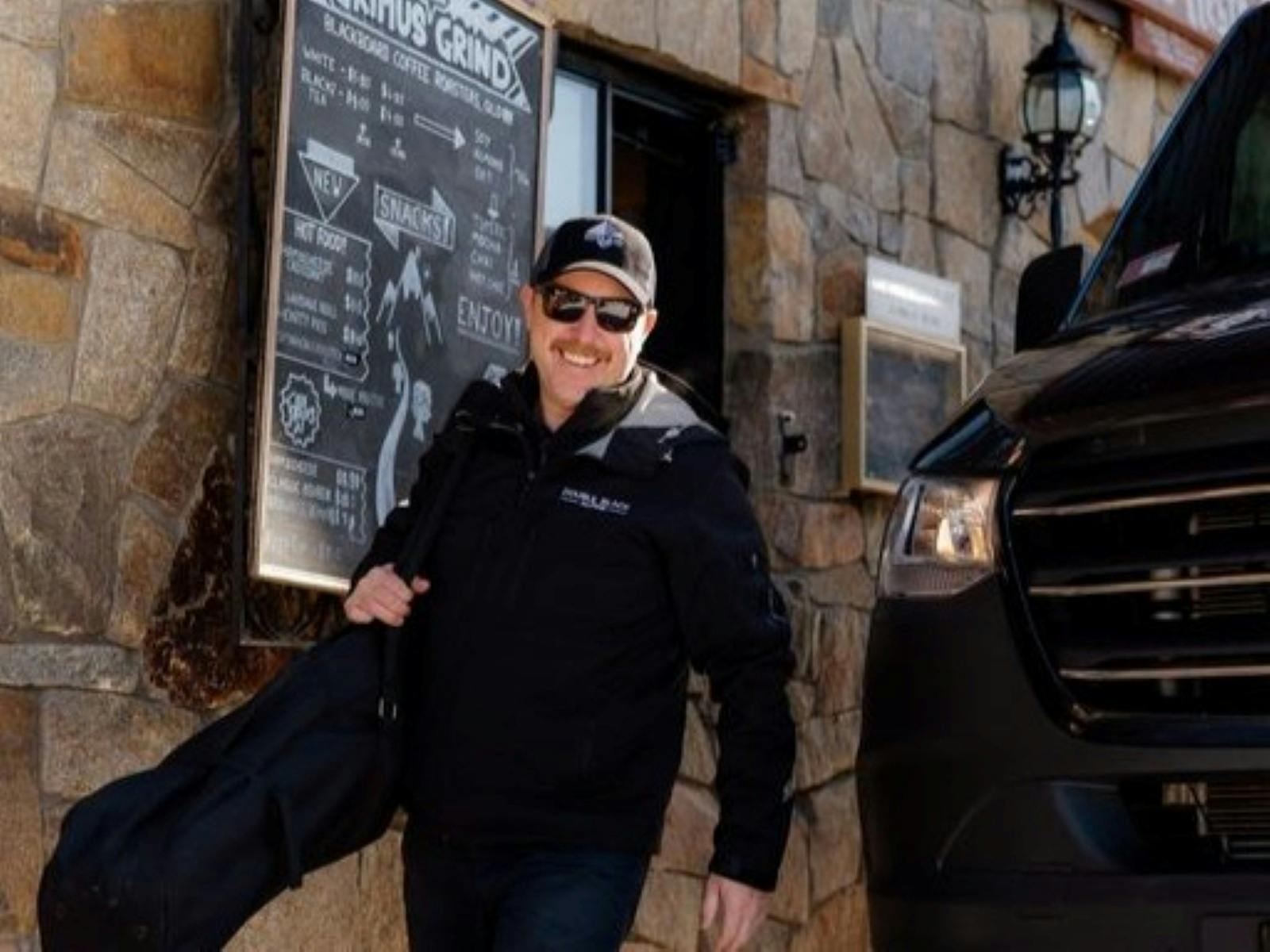 Double Black Alpine team member carries a ski bag through fresh Mount Buller snow
