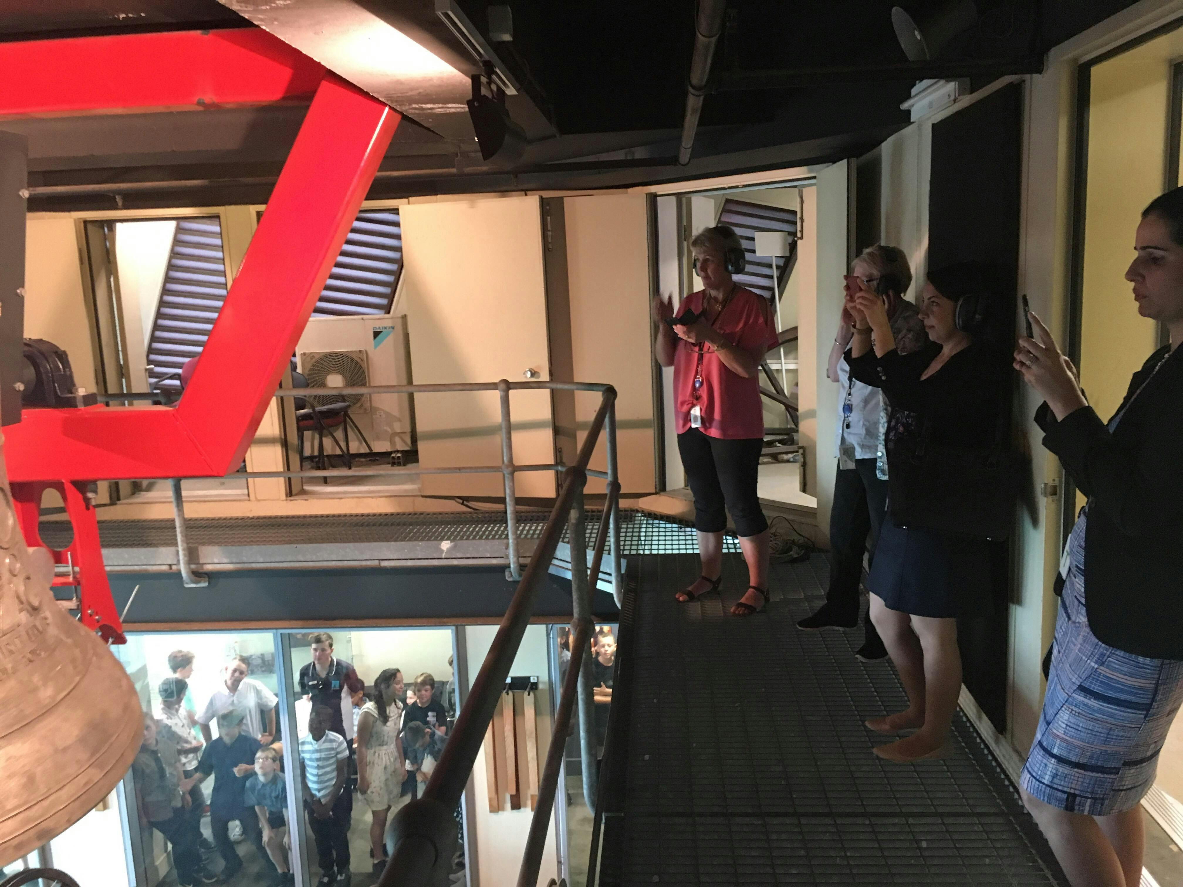 A group of people take photos of the ANZAC Bell up close in the Belfry