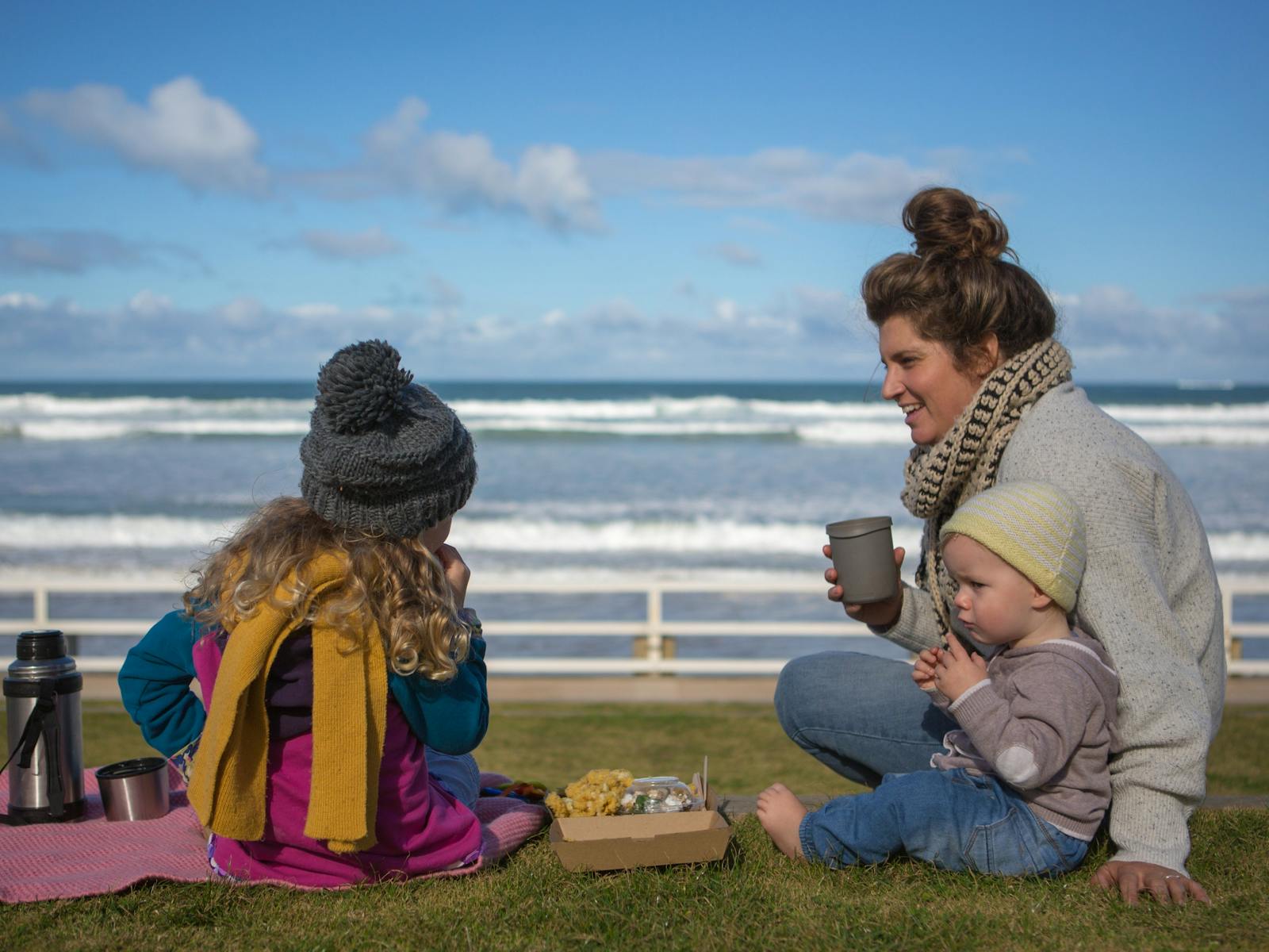 A family enjoying a beach picnic at Ocean Grove Main Beach in the cooler months