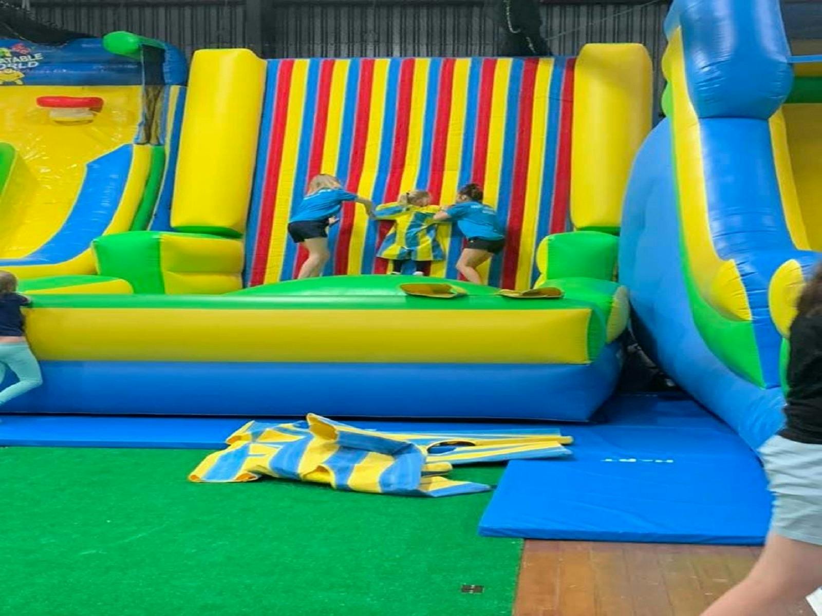 Image of staff helping kids to slide down the inflatable slide