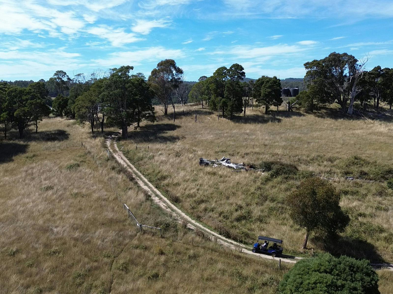 Aerial of a paddock with a motorized cart driving across it.