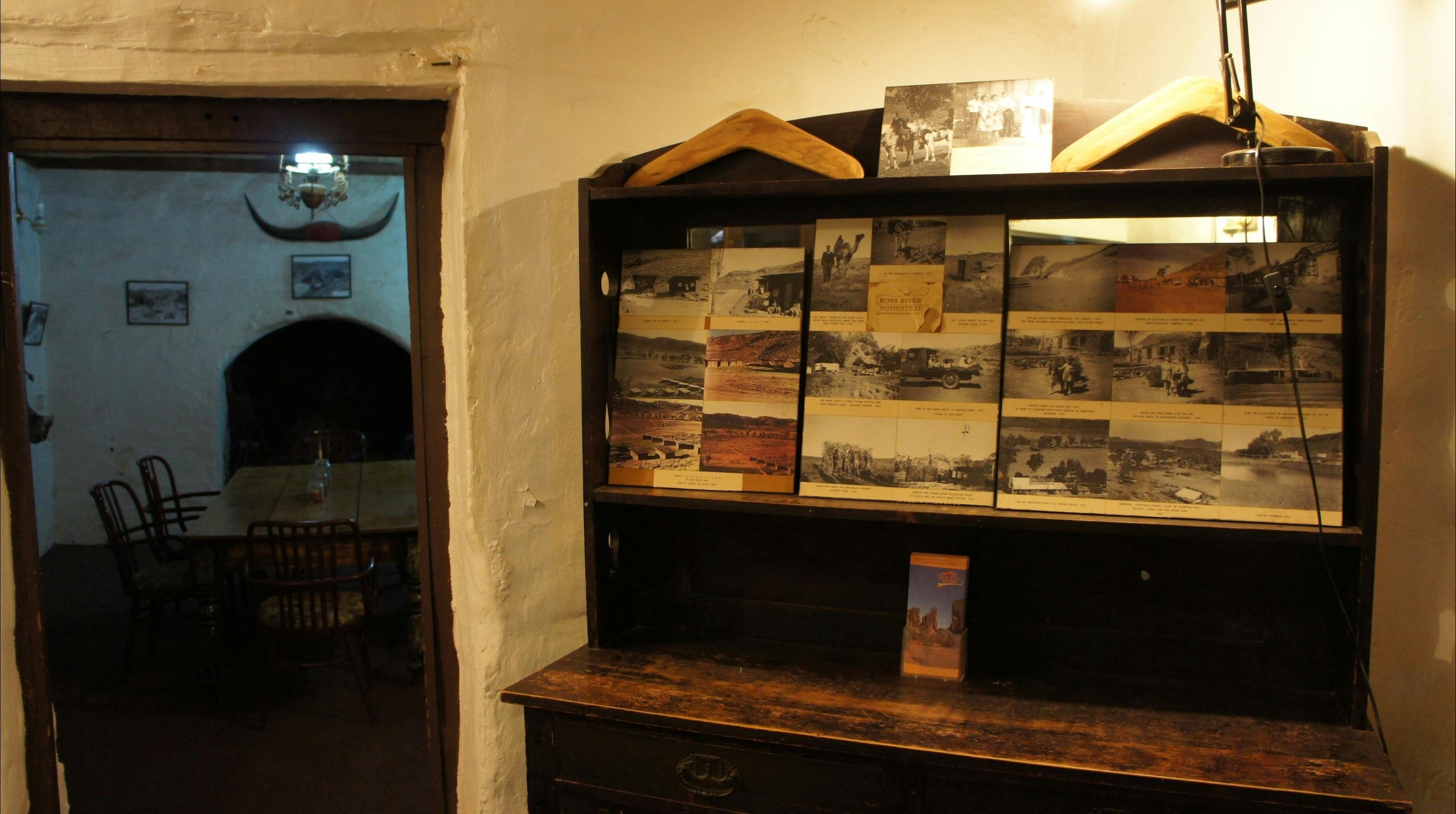 Interior of old homestead building, furnished in period pieces, and displays of photos.
