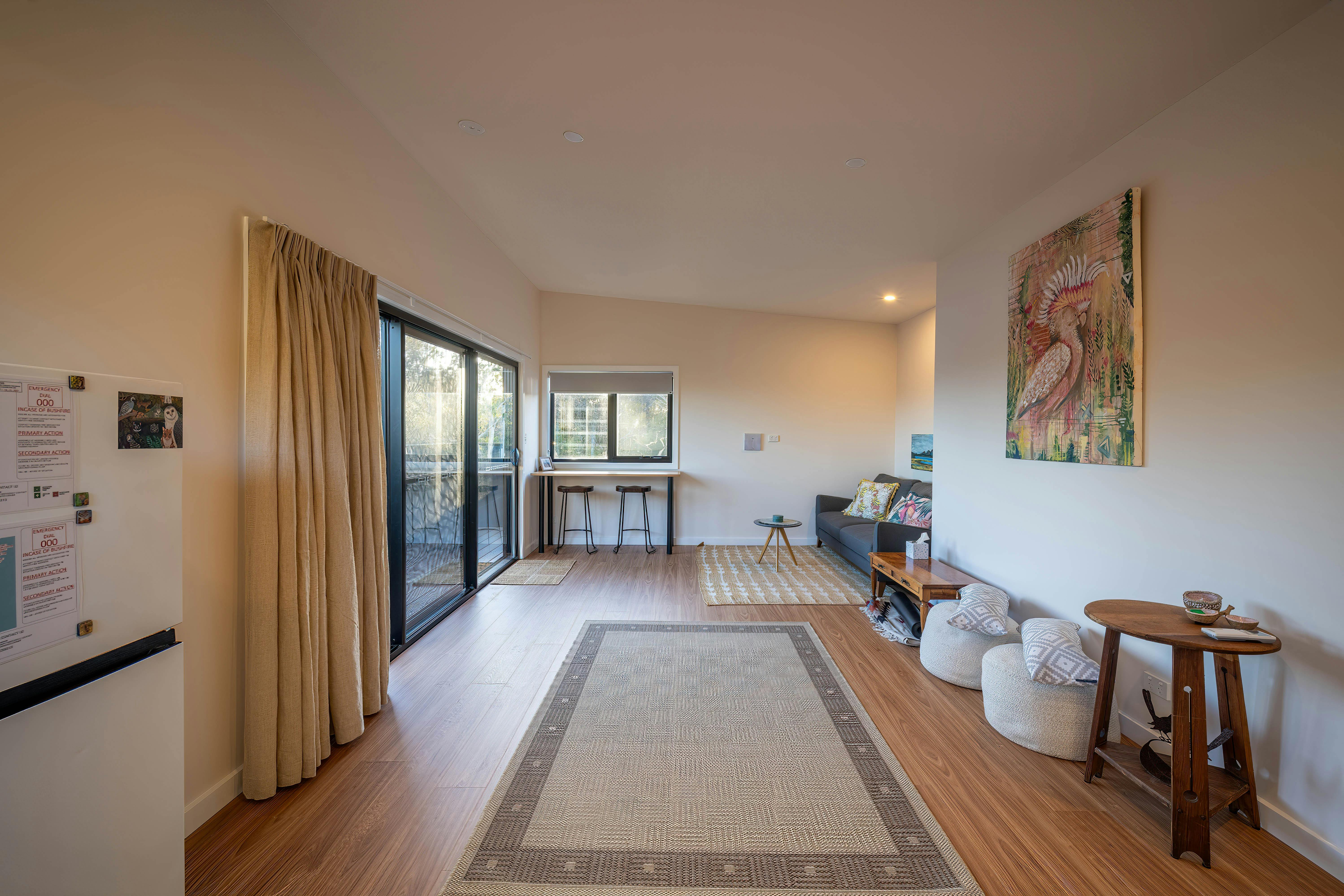 A living room with a mat, lounge and table and chairs and cushions