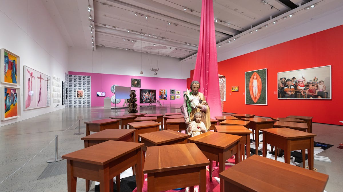 A unique art exhibition including desks randomly pushed together.