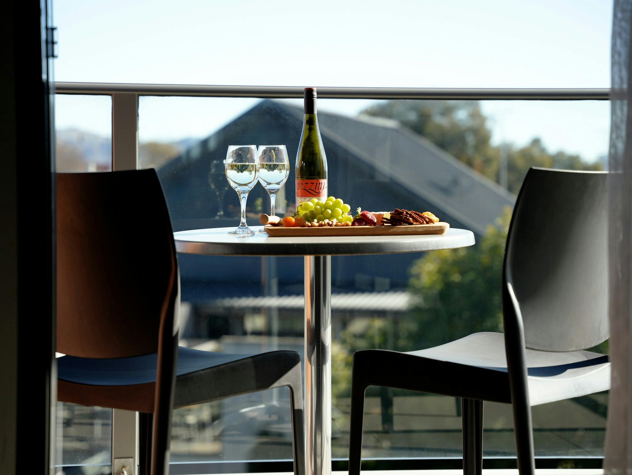A balcony table and chairs, topped with wine and a platter, overlooking the view of the restaurant