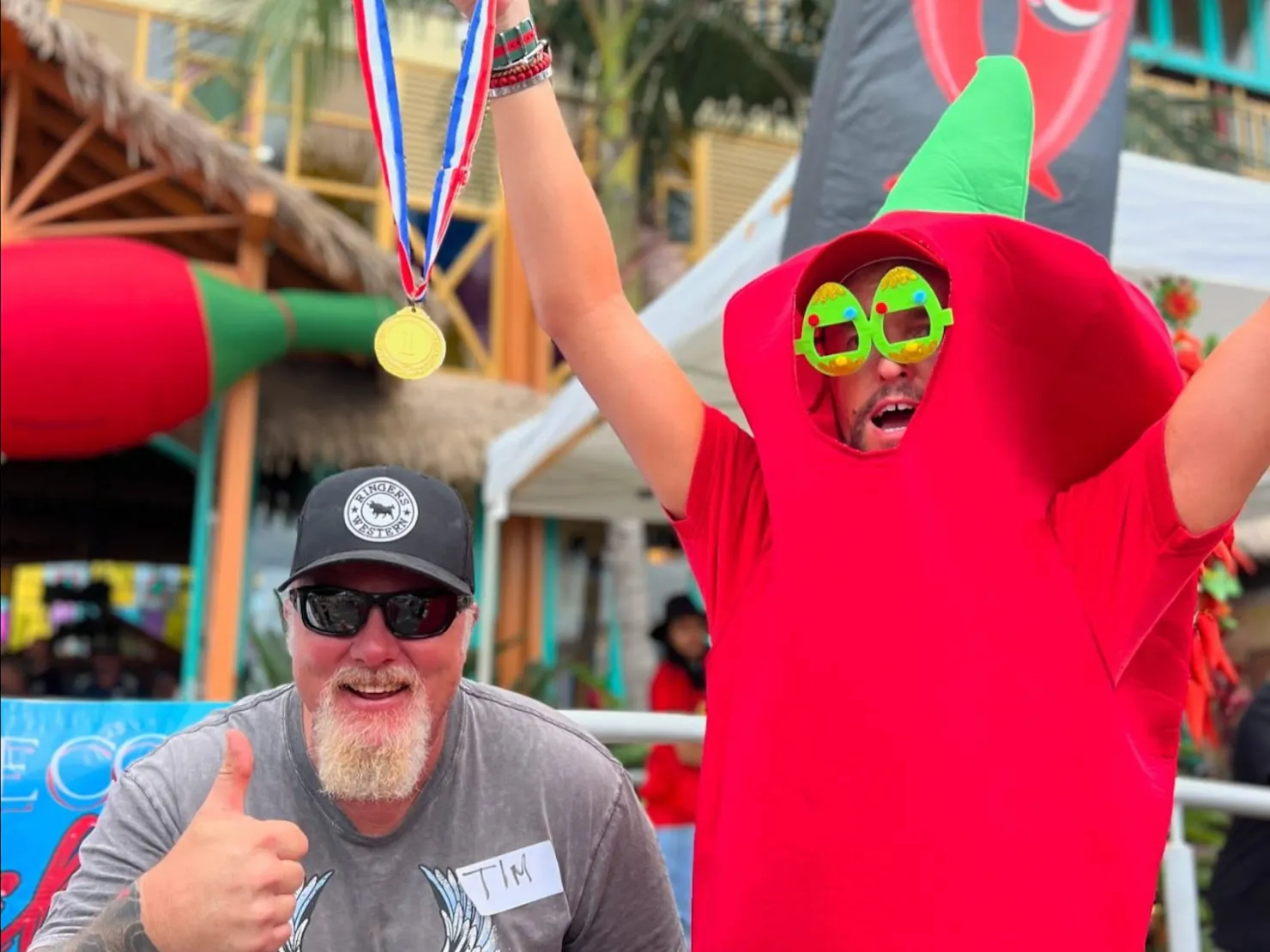 A man in a chilli costume and another man smiling at the camera