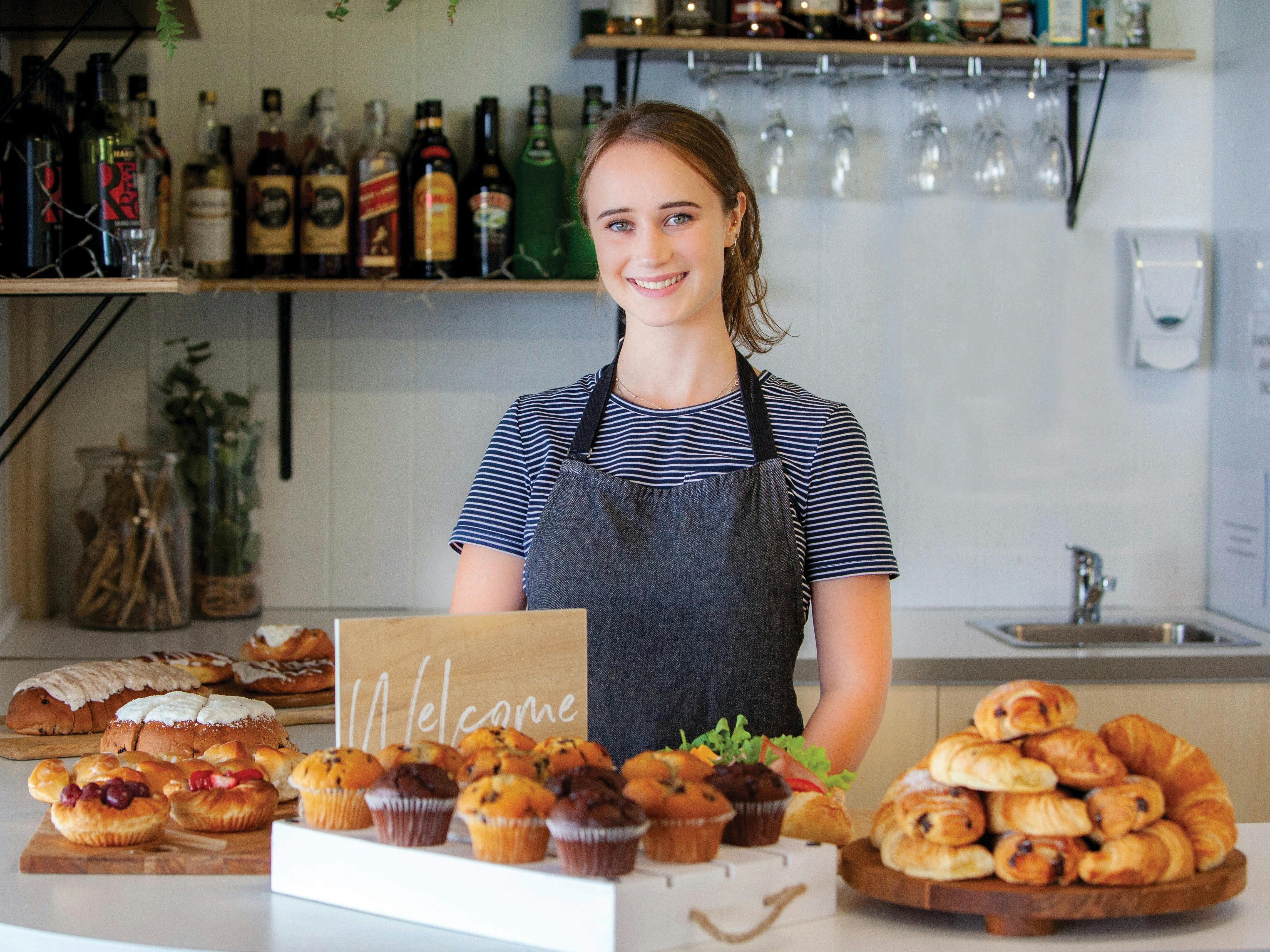 Woman working at cafe in front of pastries