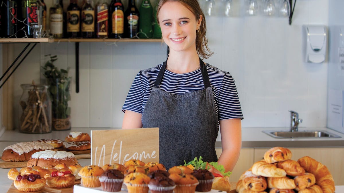 Woman working at cafe in front of pastries