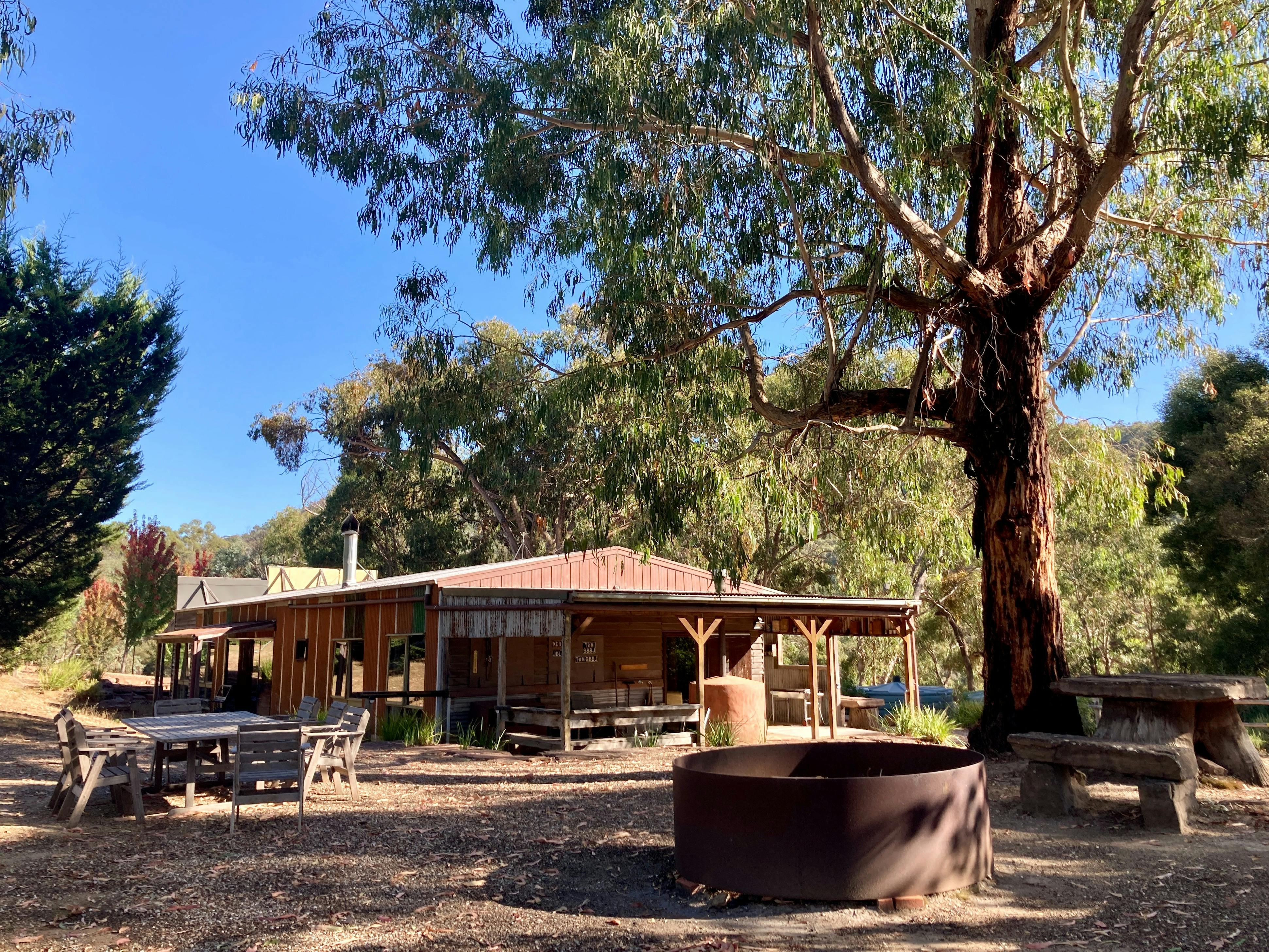 Large outdoor fire pit and seating with The Stables accommodation in background