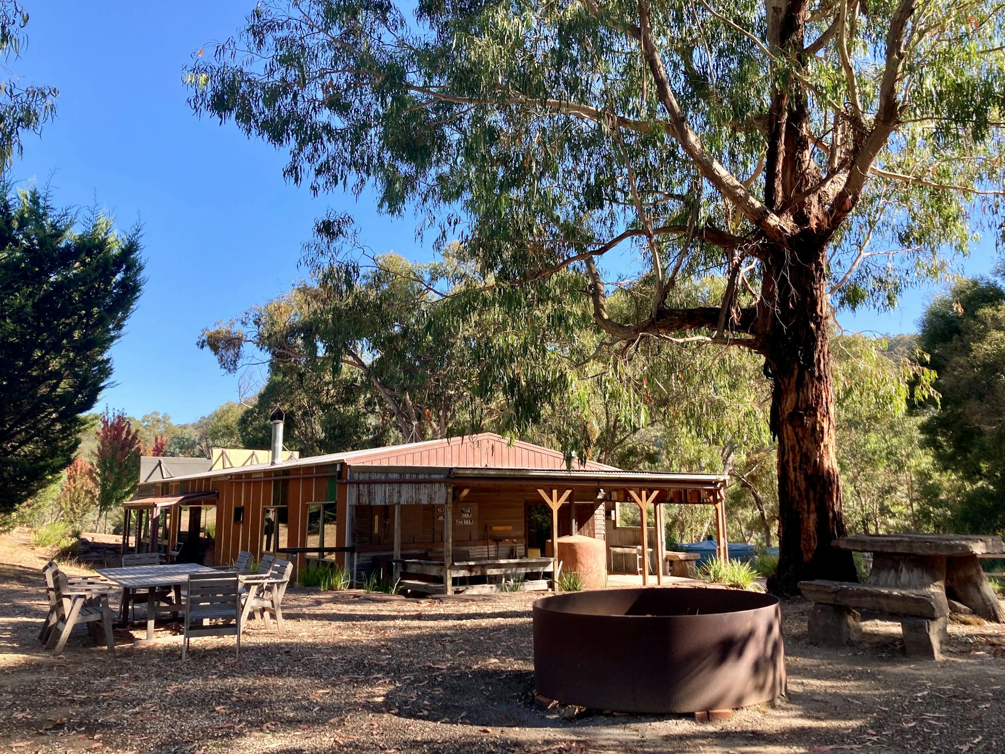 Large outdoor fire pit and seating with The Stables accommodation in background
