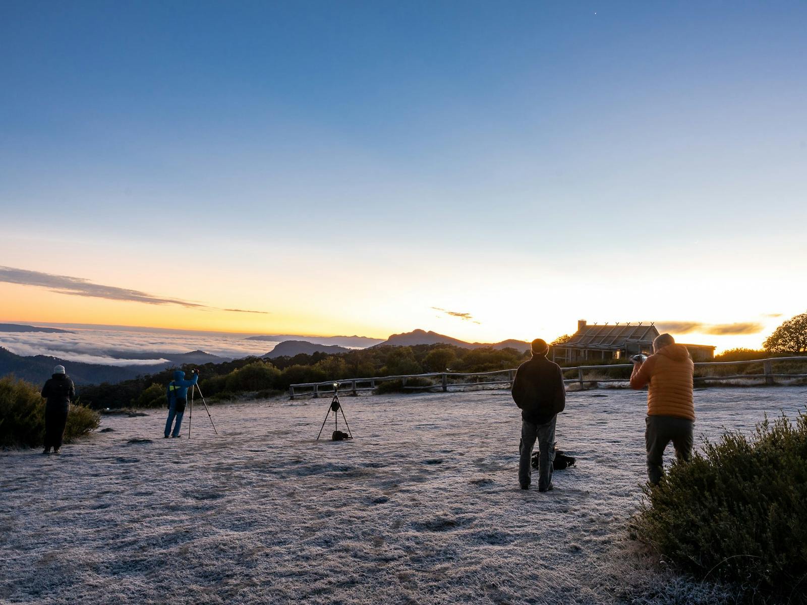 A group of hikers on a frosty morning at Craig's Hut receiving photography tips.