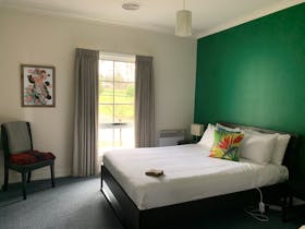 A queen bed and a single bed in a room with a green wall