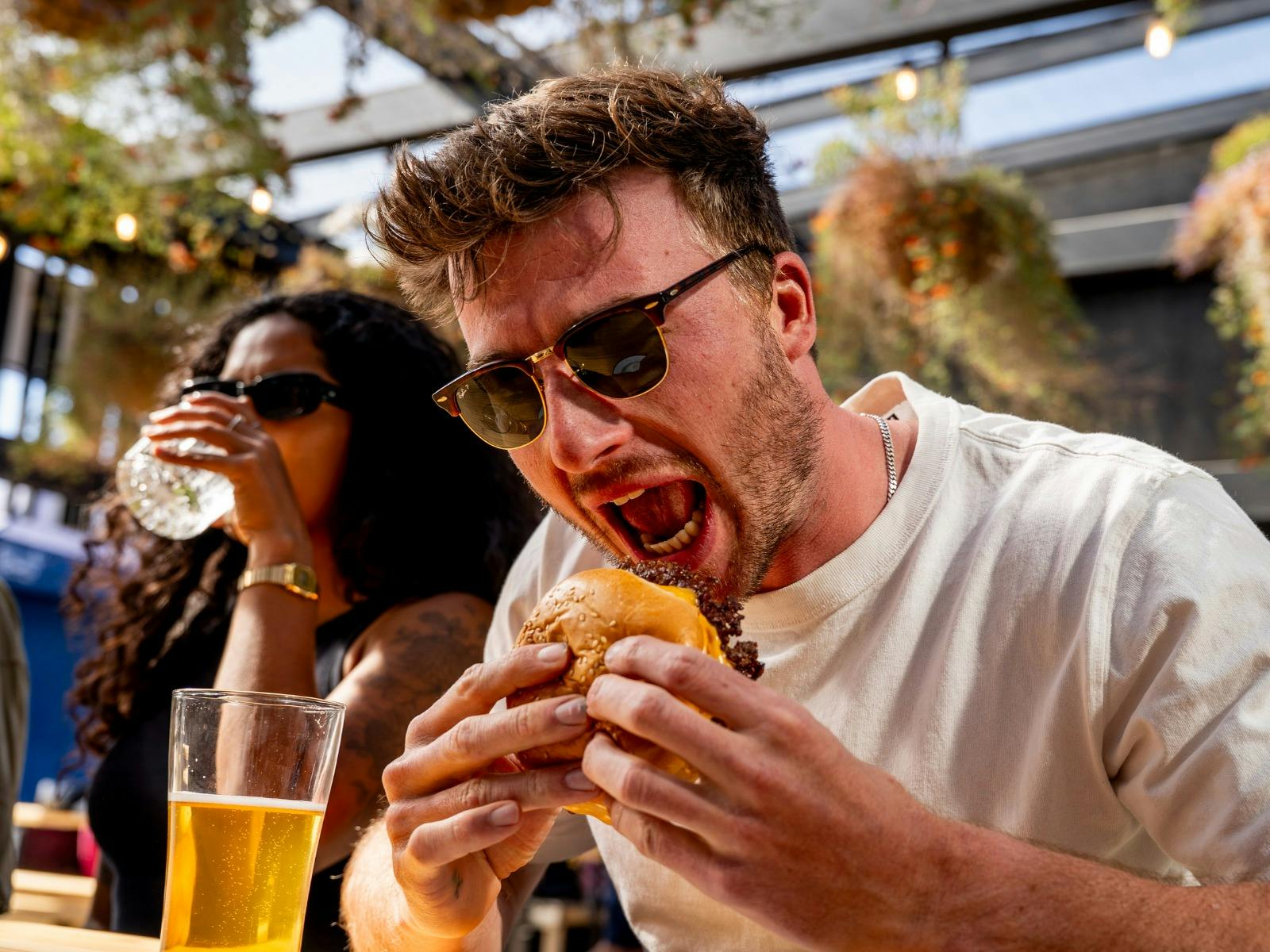 Man eating a burger outdoors at Breeze Burgers, Easy Tiger, St Helens.