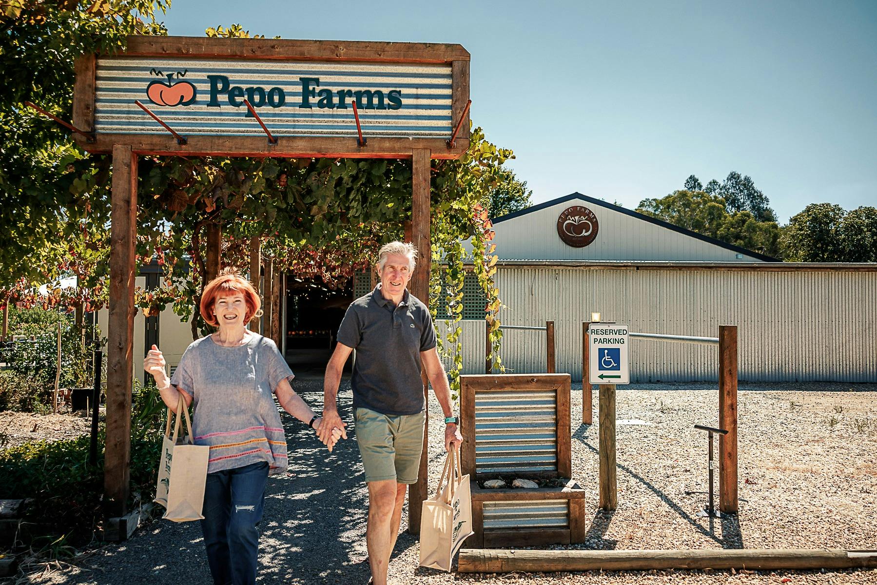 Couple with bags of product walking from shop to carpark at Pepo Farms
