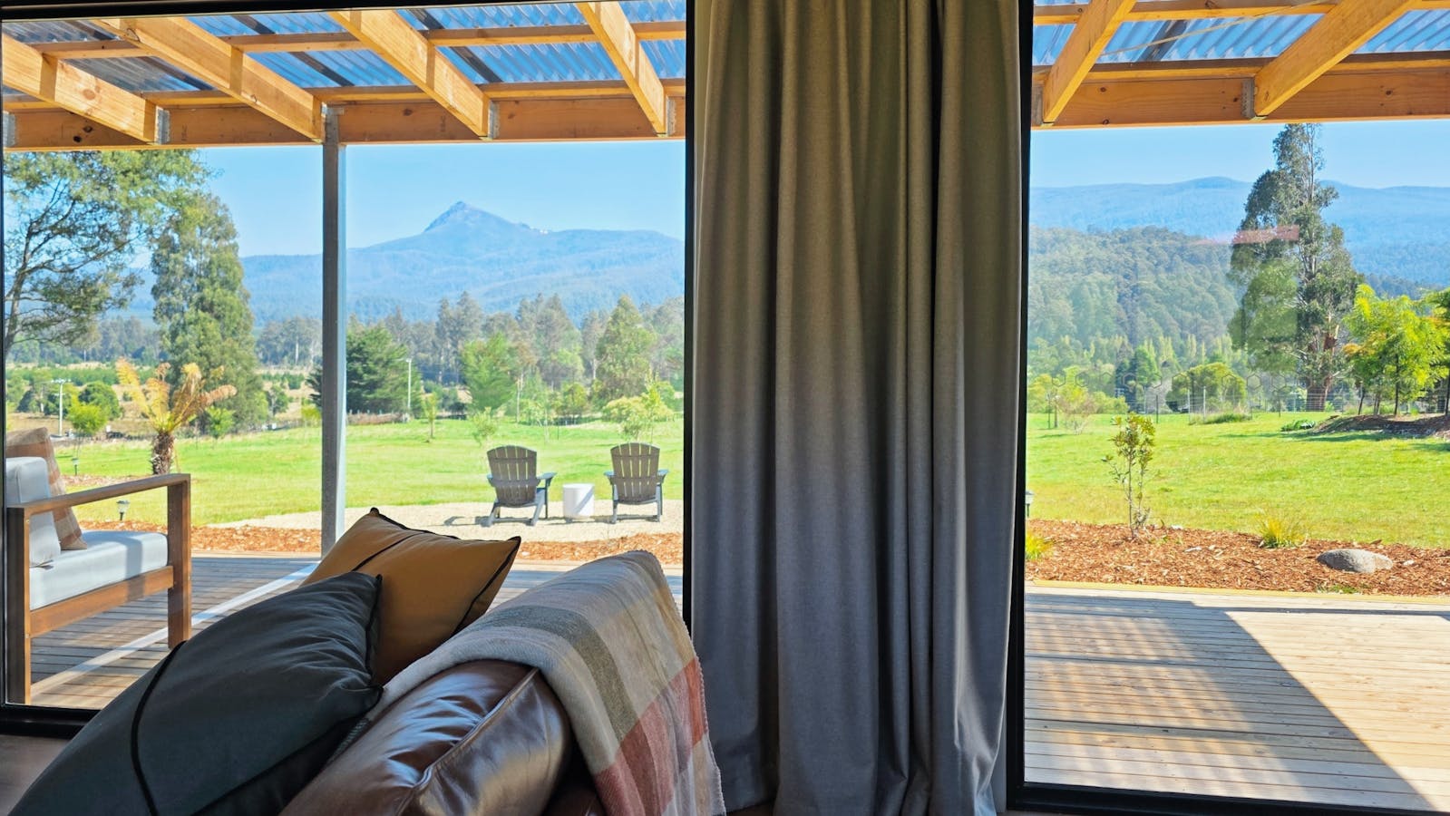 Light-filled living room with picture windows framing the gardens, forest and mountain views