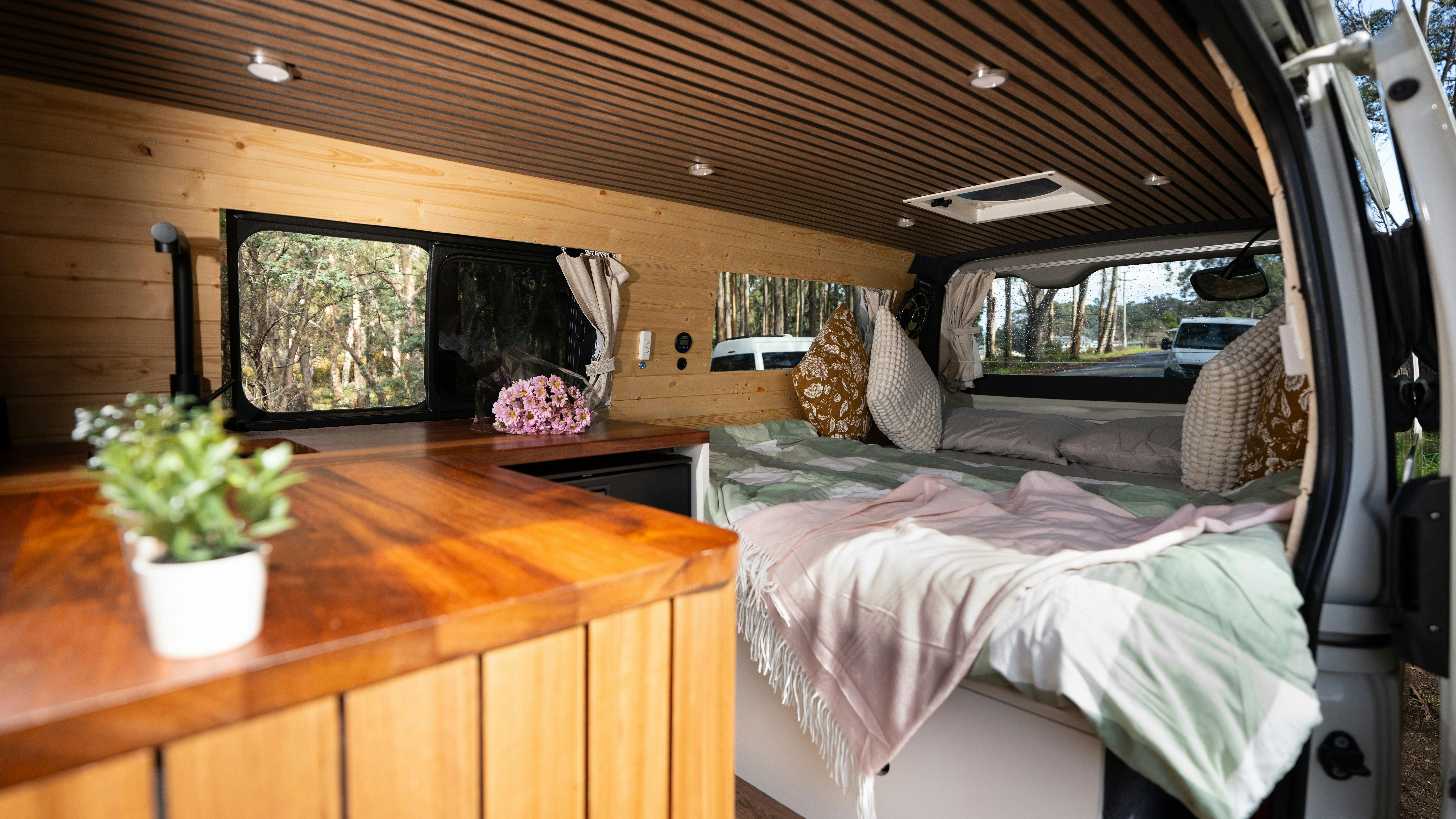 Rustic timber interiors of Yana van showing panoramic bed and comfortable layout.