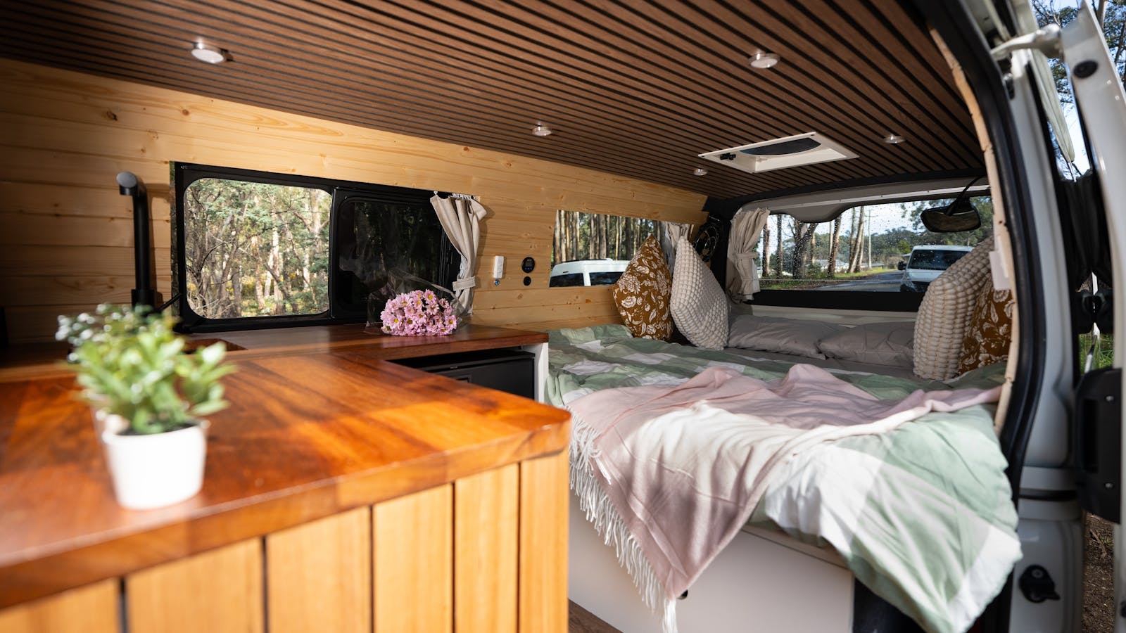 Rustic timber interiors and panoramic bed views for cozy off-grid van life adventures.
